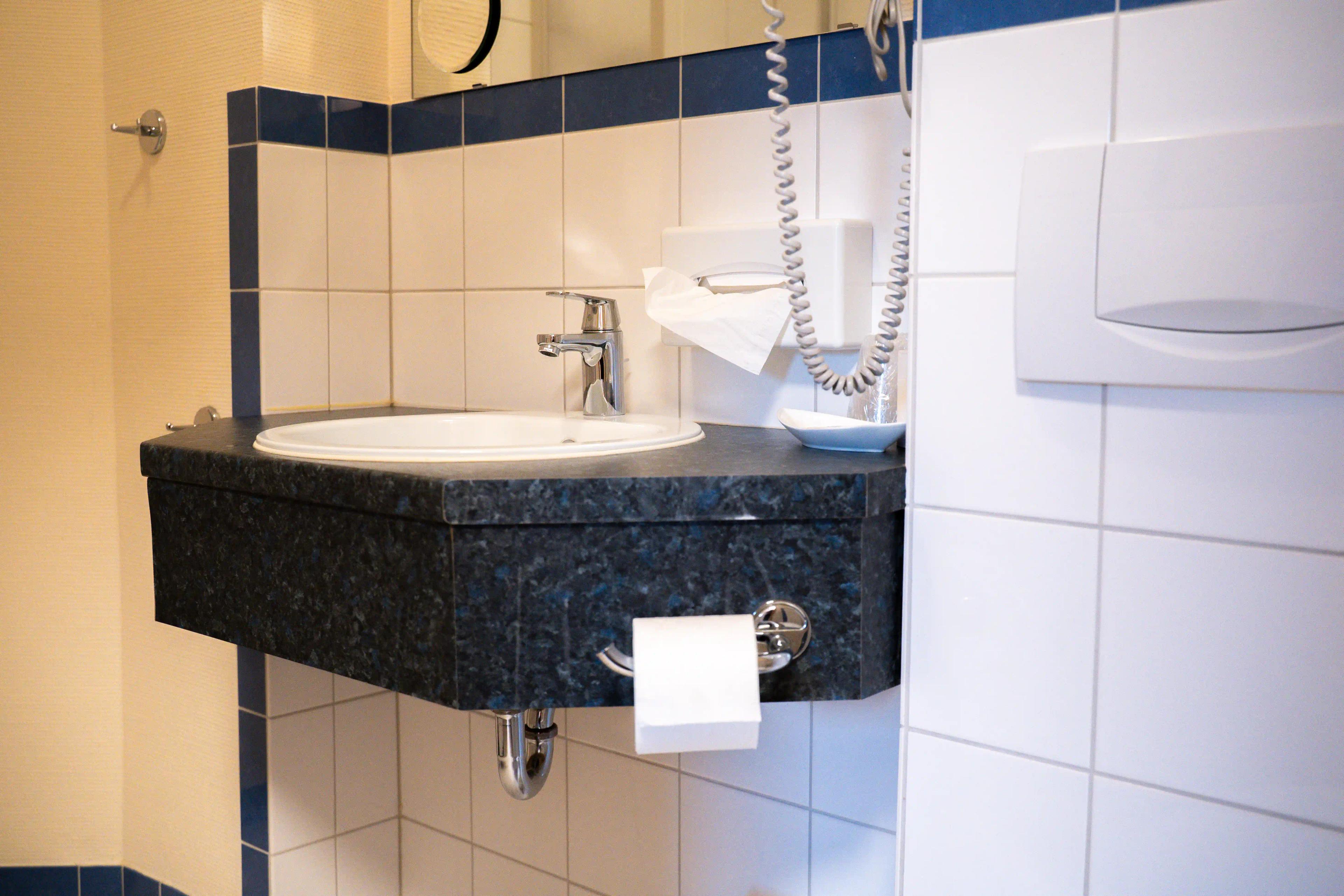 Waschbecken mit dunkler Ablage und Föhn