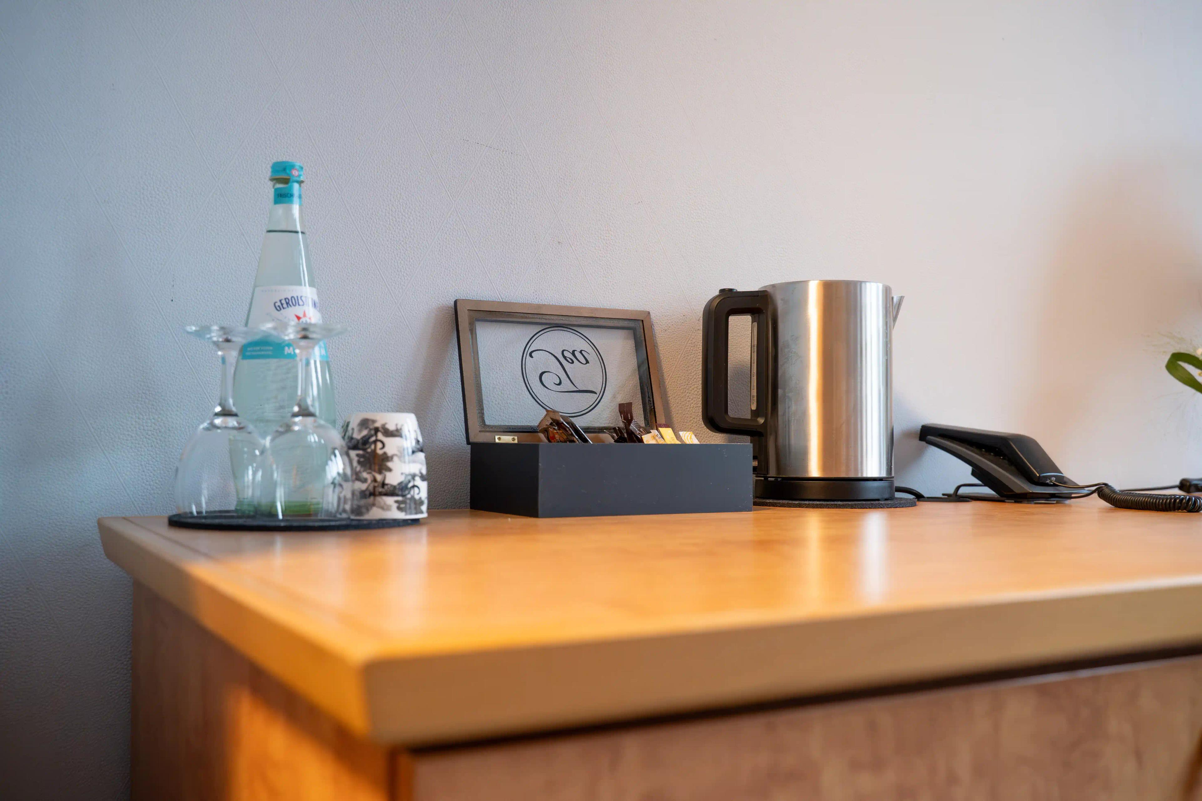 Wasserflasche, Gläser, Wasserkocher und Begrüßungskarte auf der Kommode