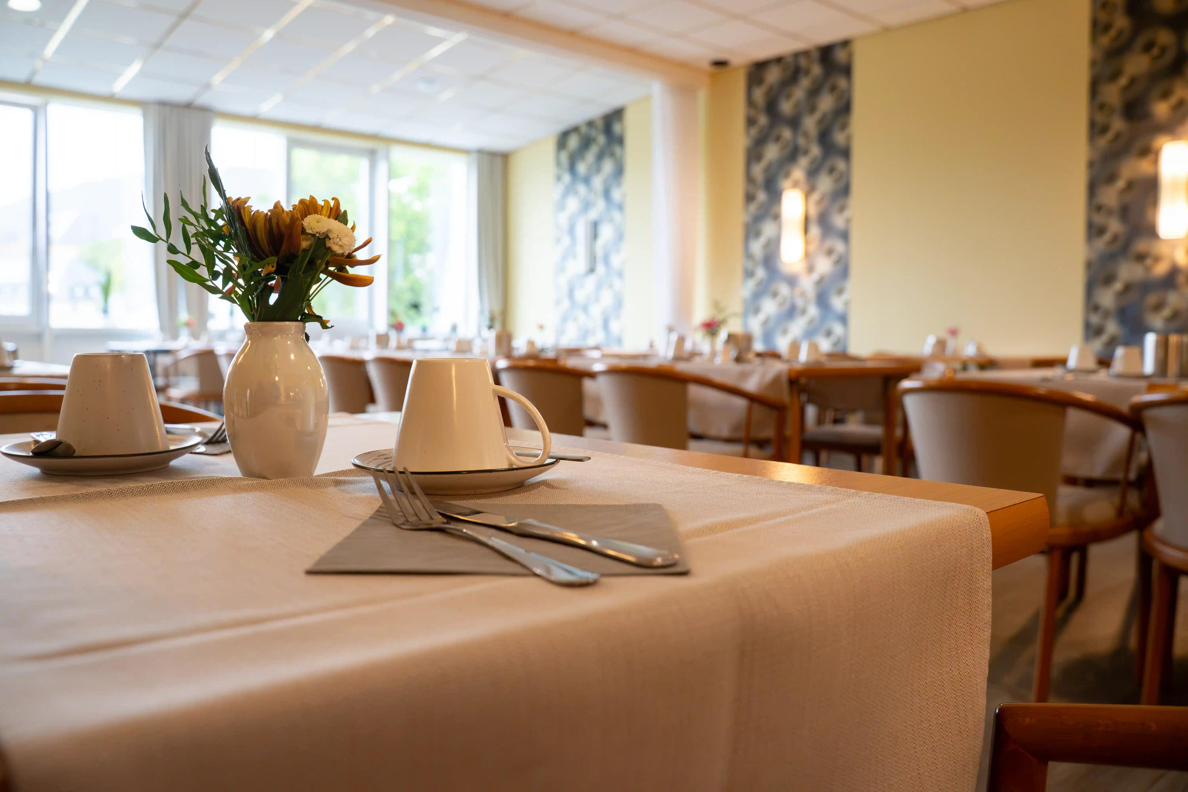 Gedeckter Frühstückstisch mit Blumen im hellen Frühstücksraum