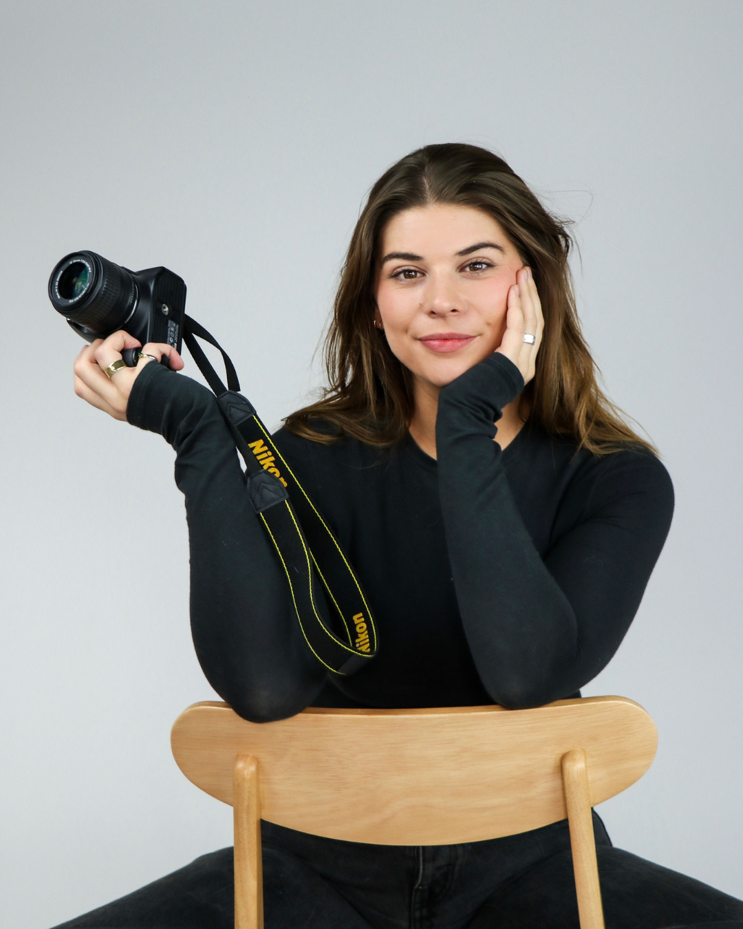 Lina de Boer met haar camera in de hand, zittend op een stoel