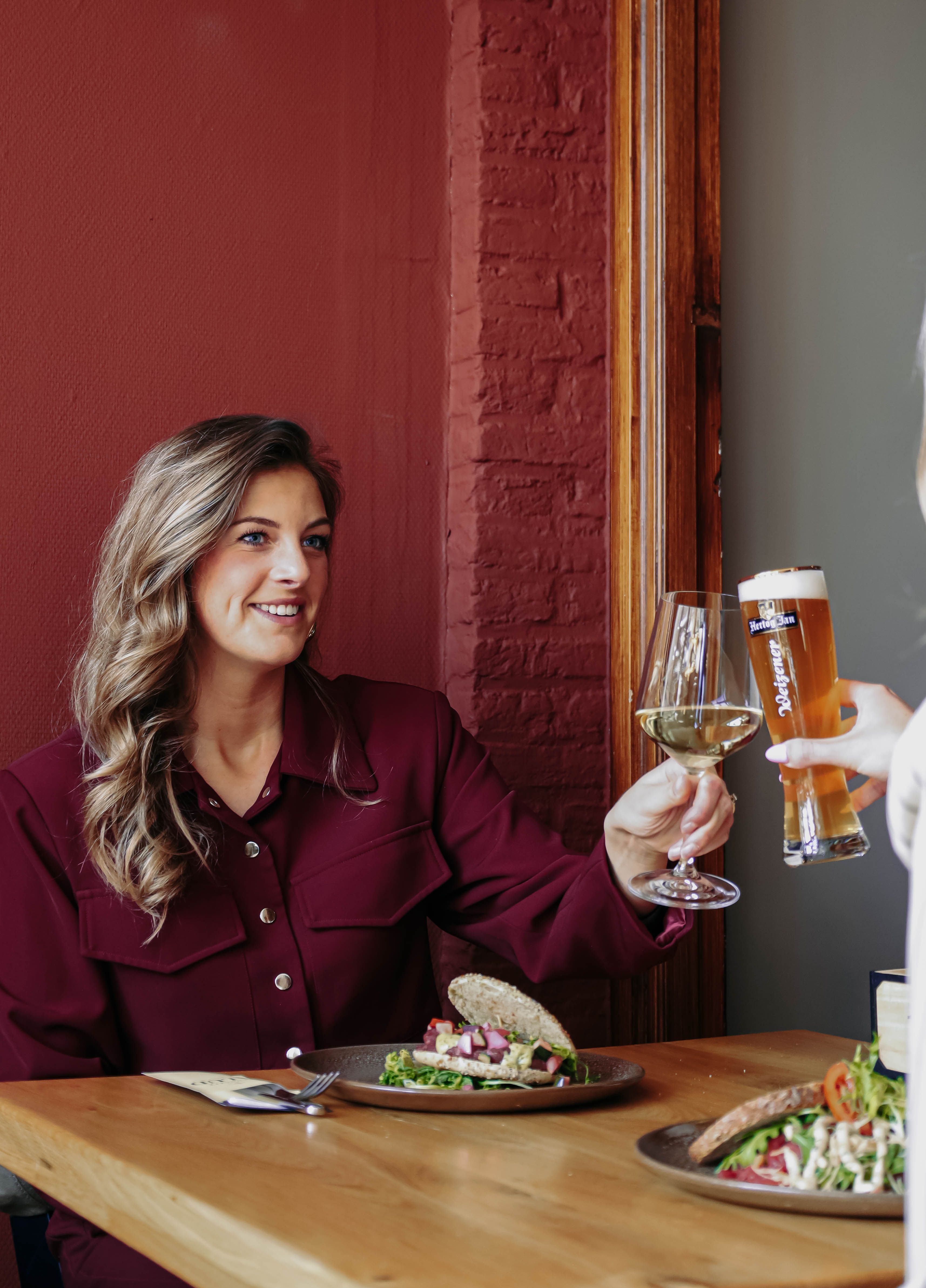 Gast aan tafel met een glas wijn in Grand Cafe Salud