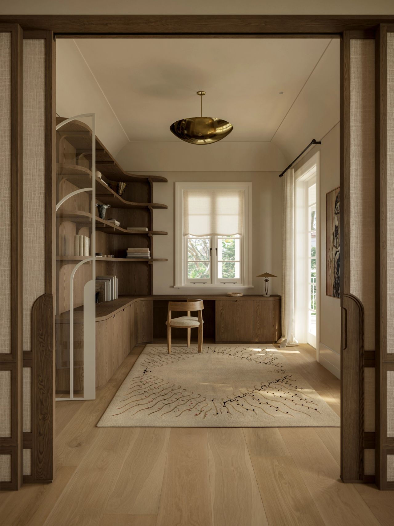 Lady M Study viewed through fabric-panelled sliding doors, featuring curved built-in timber shelving, a fitted desk with a single chair, a branch-patterned rug, and an organic sculptural brass pendant light overhead