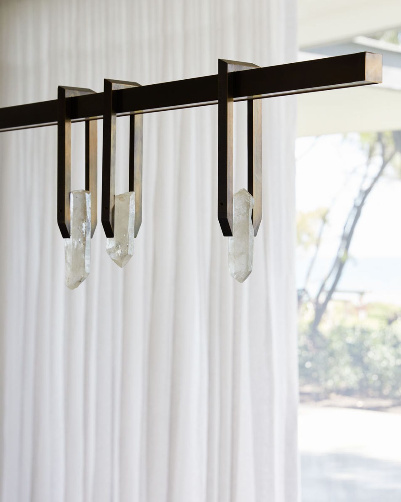 Detail of contemporary linear pendant light with dark metal frame and suspended crystal details.