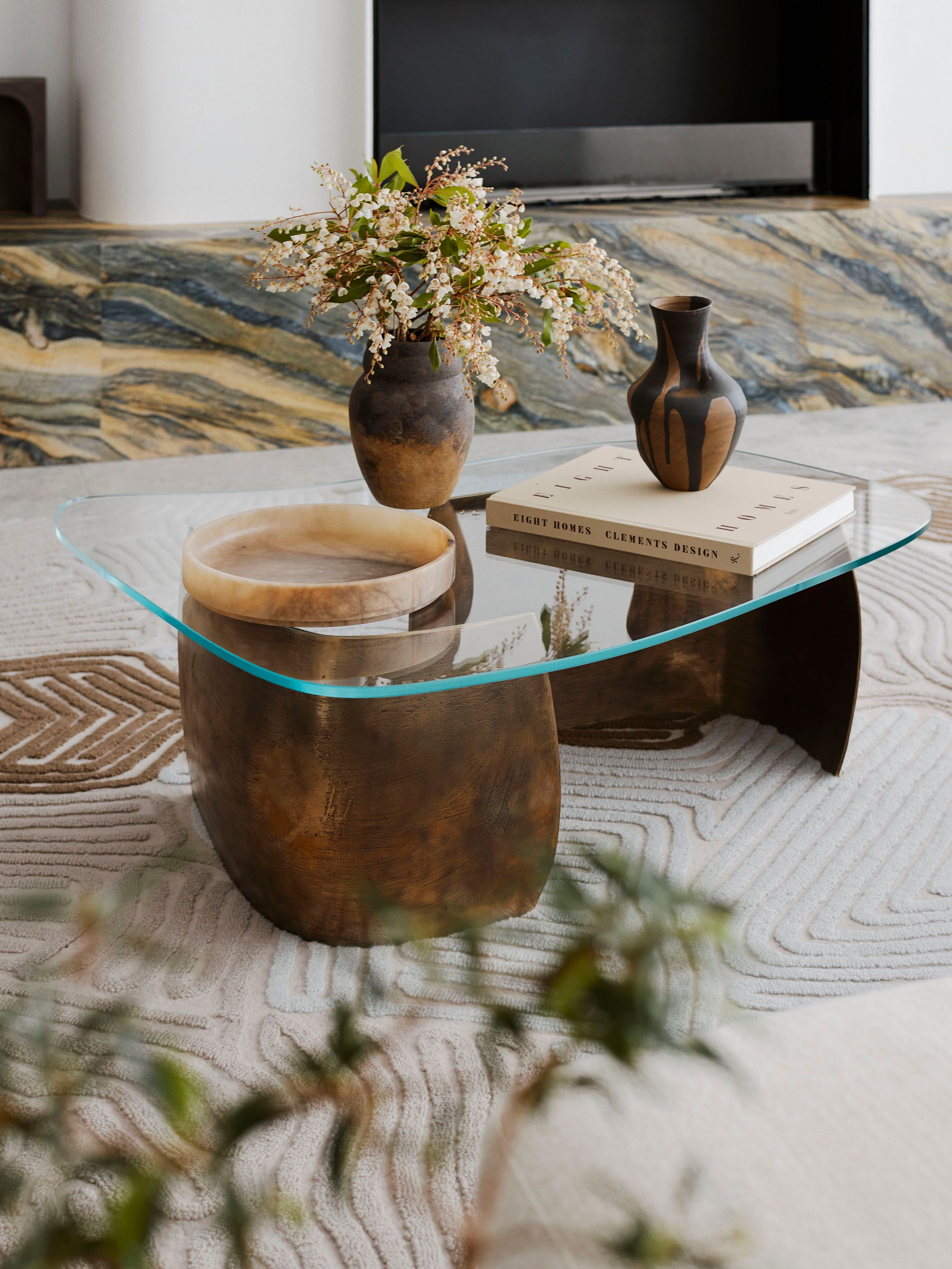 Sculptural glass coffee table styled with ceramic vessels, flowers and decorative objects at Cloud Surfer, a richly textured Broadbeach penthouse by Decus.