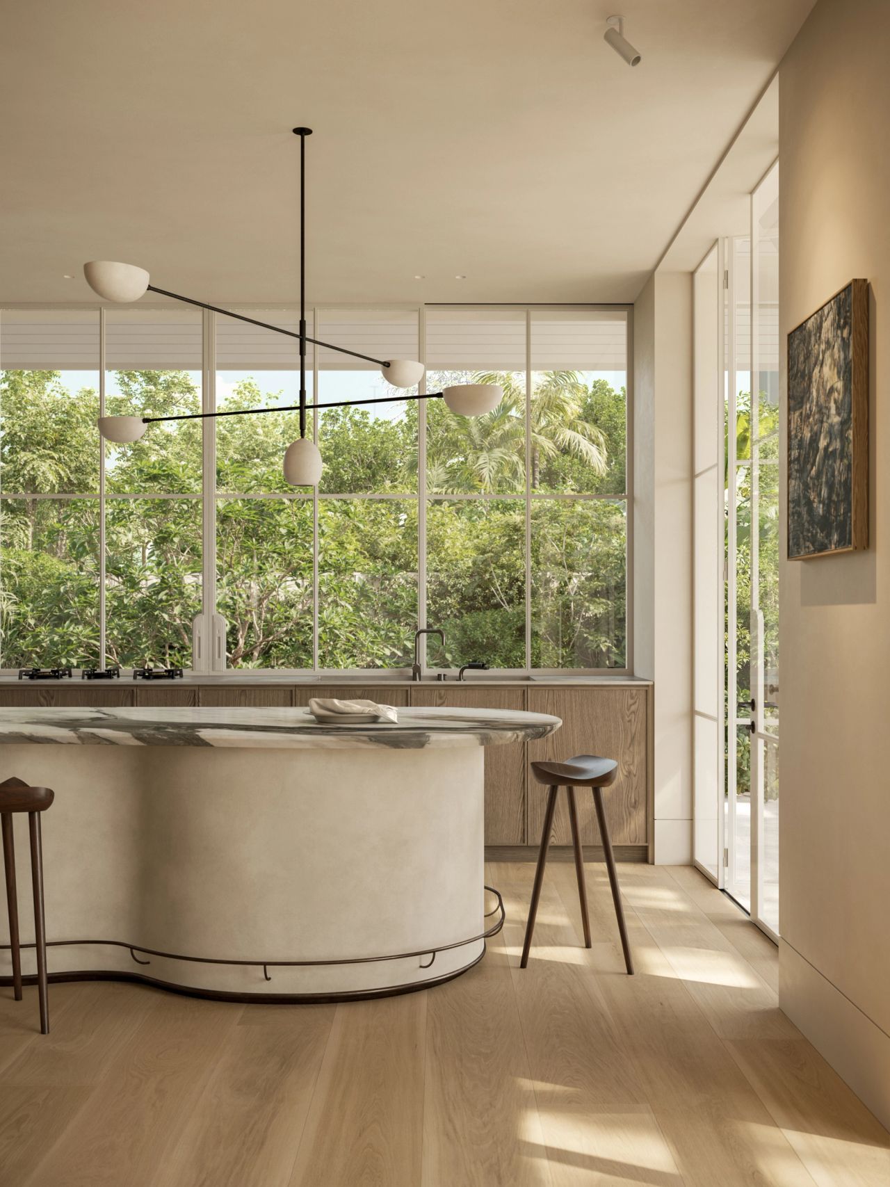 Kitchen with a curved marble-topped island and plaster-finish base, timber cabinetry, and a sculptural multi-arm pendant light with matte white shades. Floor-to-ceiling windows frame lush garden greenery, with timber bar stools and framed artwork completing the space.
