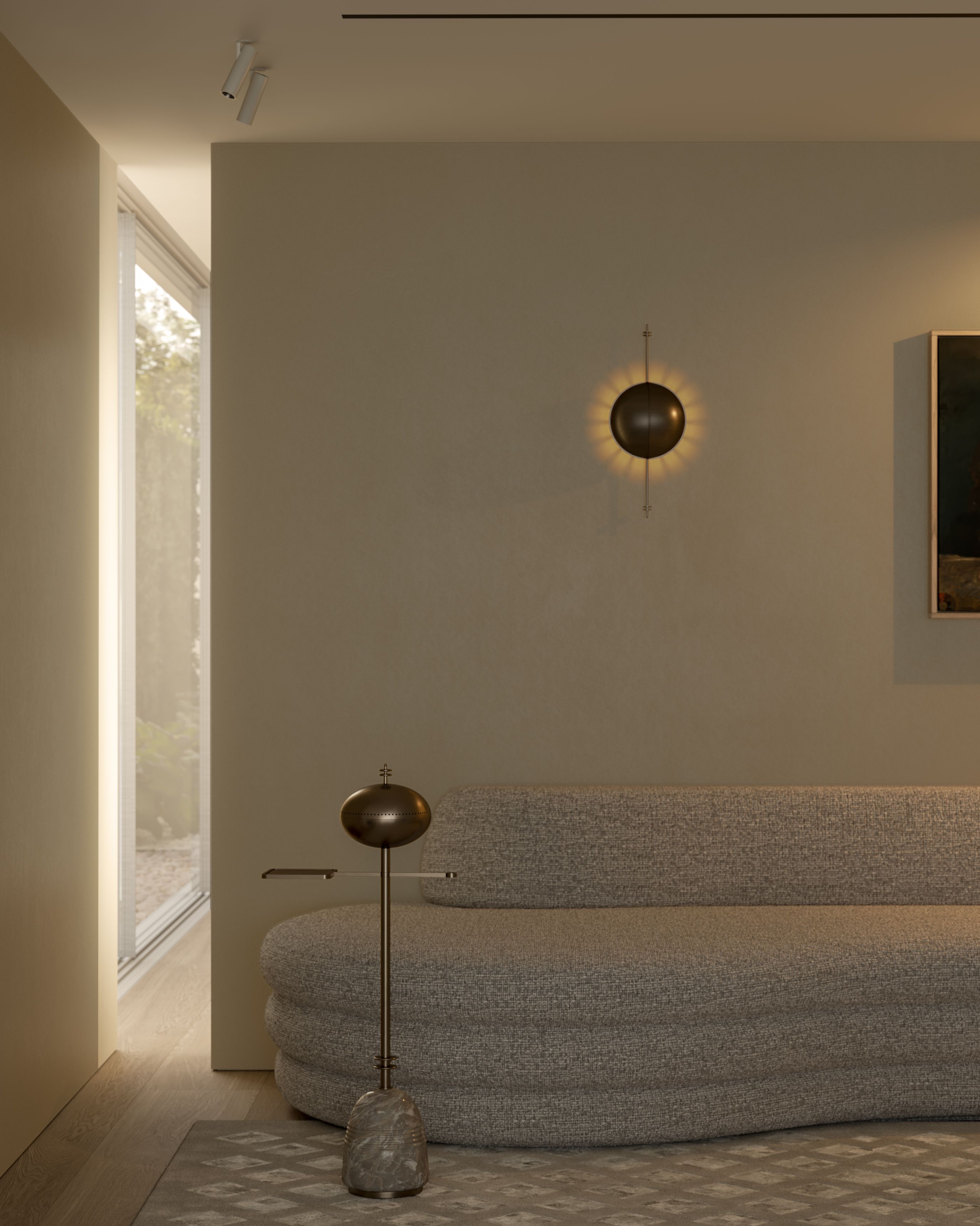 Contemporary sitting room with sculptural curved sofa, bronze floor lamp and wall sconce, patterned rug and warm natural light.