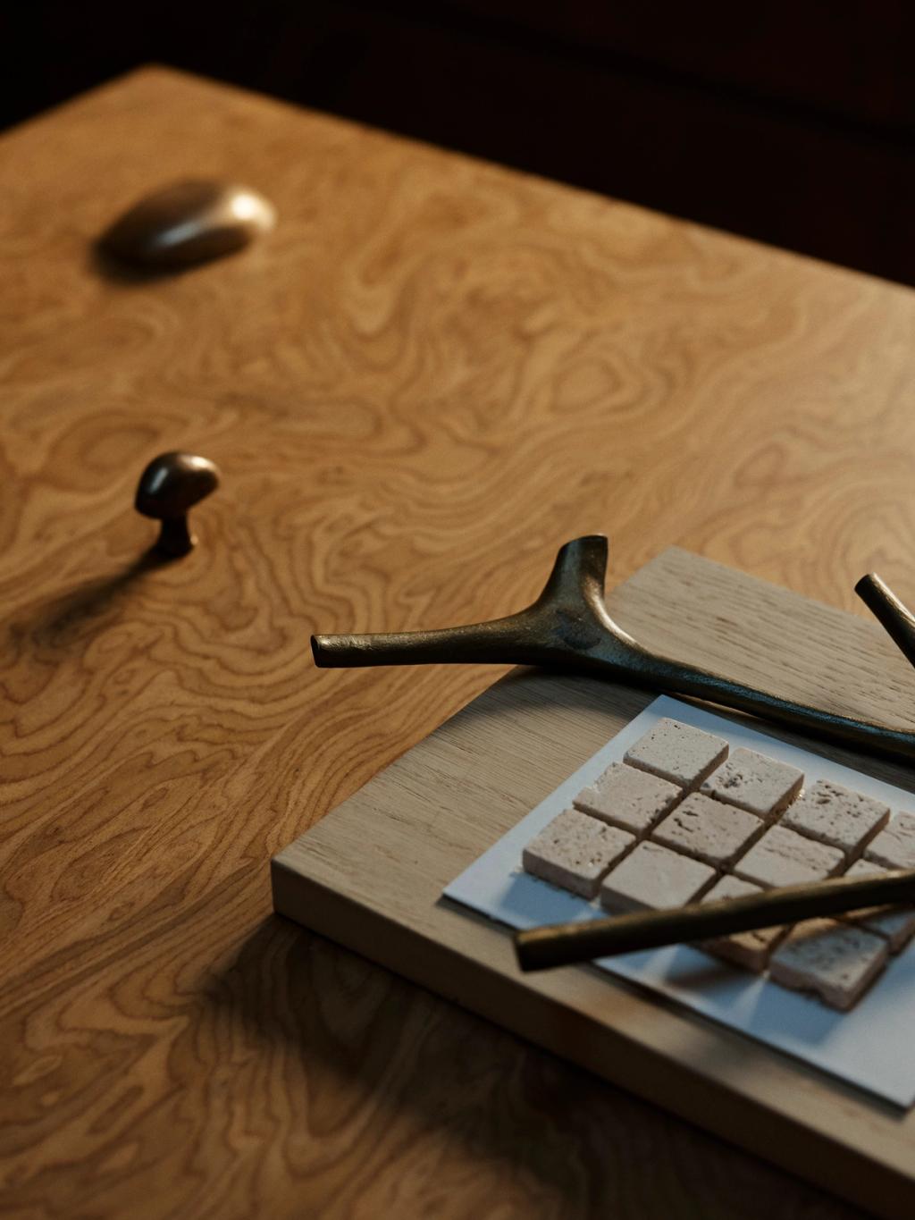 Assorted material and hardware samples displayed against burl timber veneer in decus studio