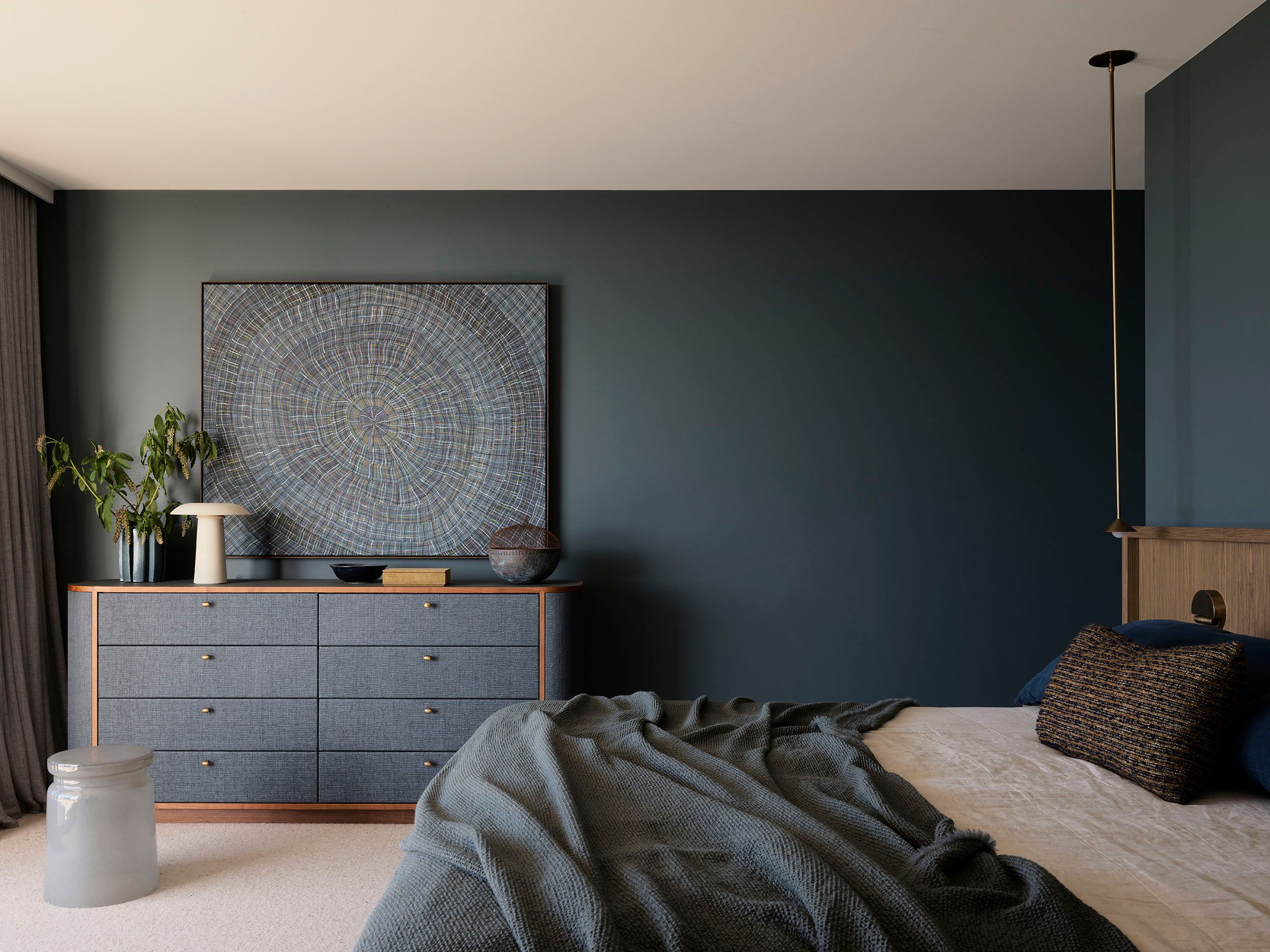 Deep ocean-blue walls envelop this penthouse bedroom by Sydney interior design studio Decus, layered with bespoke timber furniture, tactile textiles and large-scale artwork.