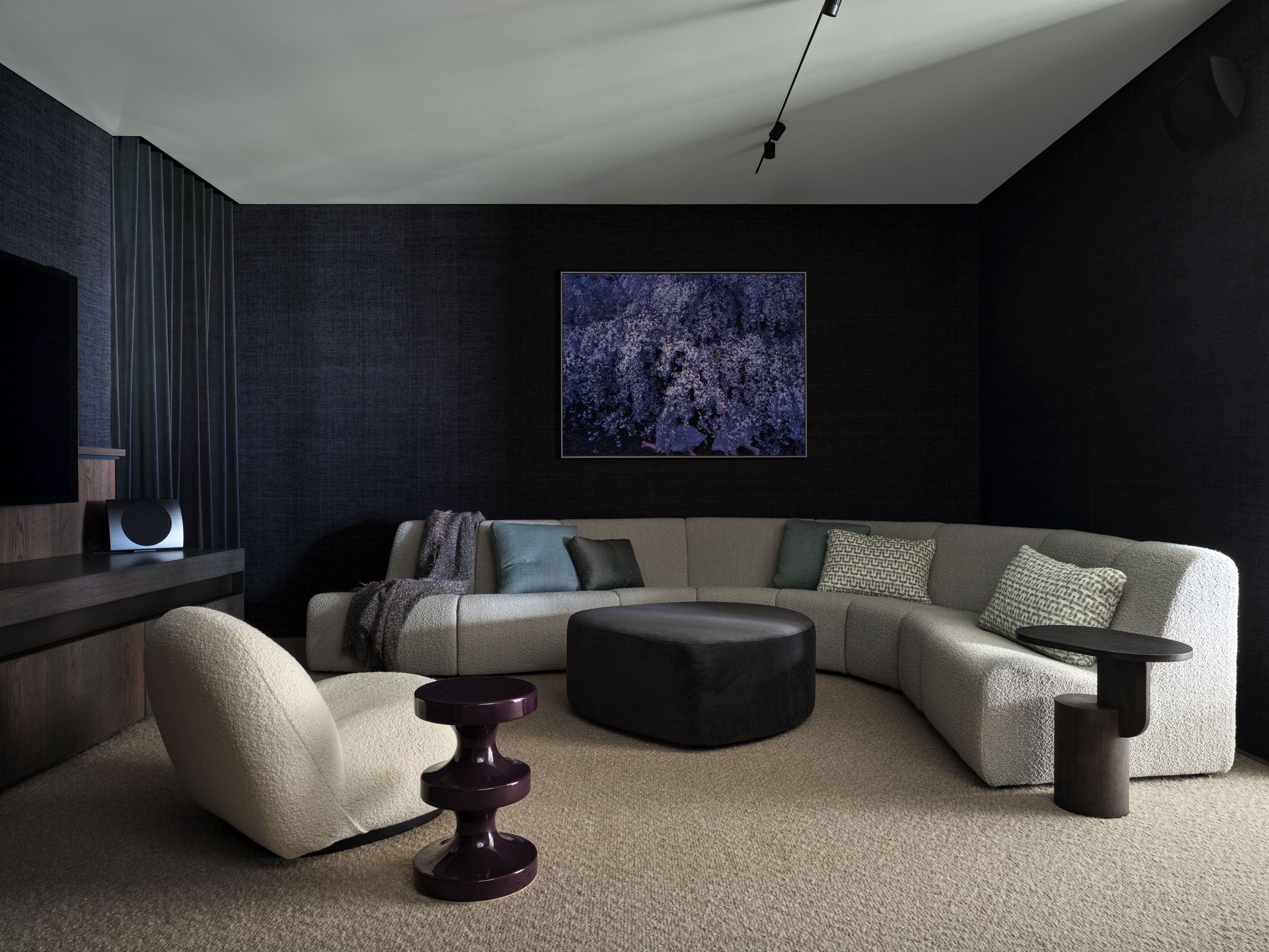 A cocooning family retreat layers curved boucle seating, sculptural furniture and rich textiles against dark tactile walls.