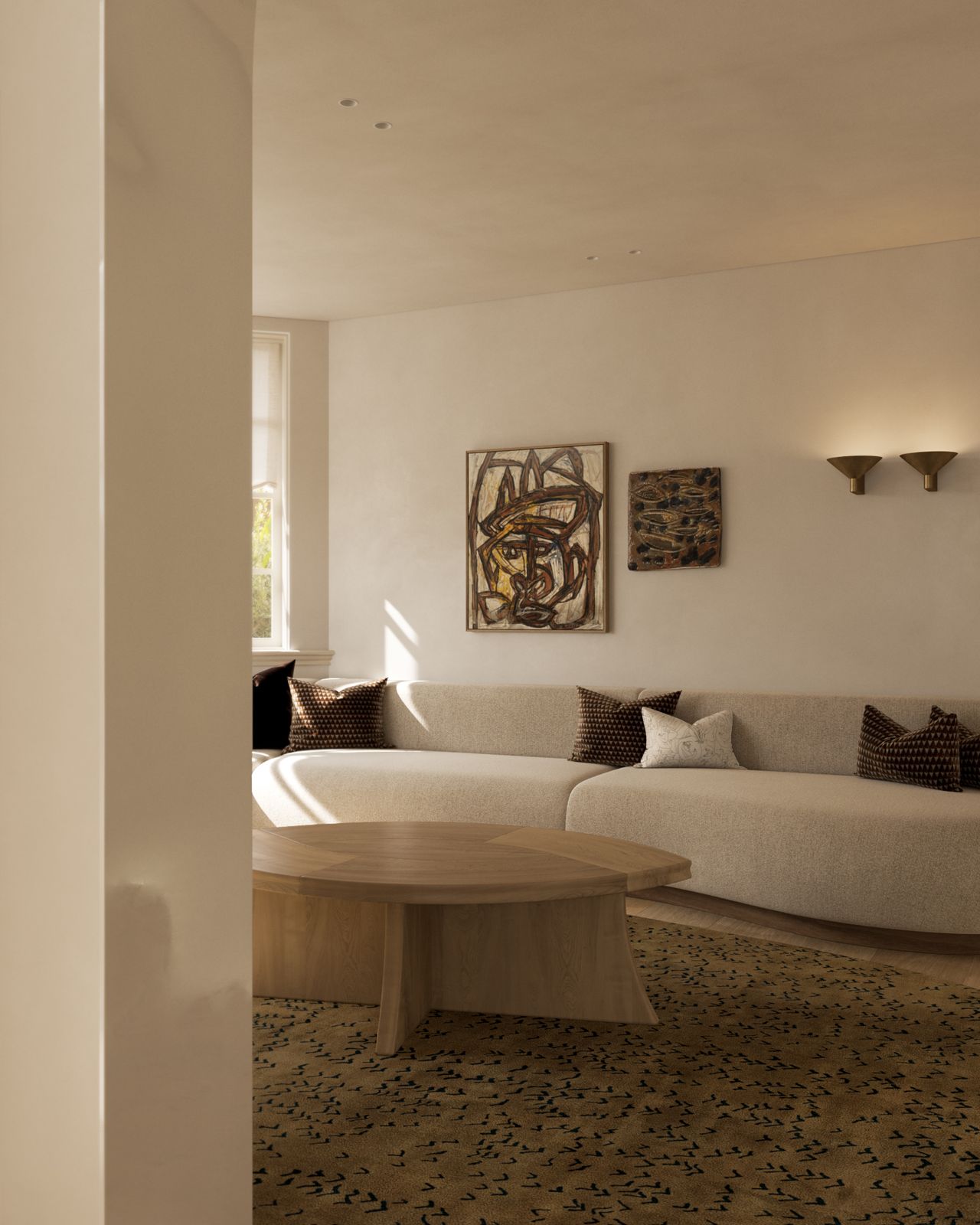 Lady M Living area with a curved cream boucle sofa styled with patterned cushions, a round sculptural timber coffee table, a patterned dark-toned rug, and two abstract artworks flanked by brass wall sconces