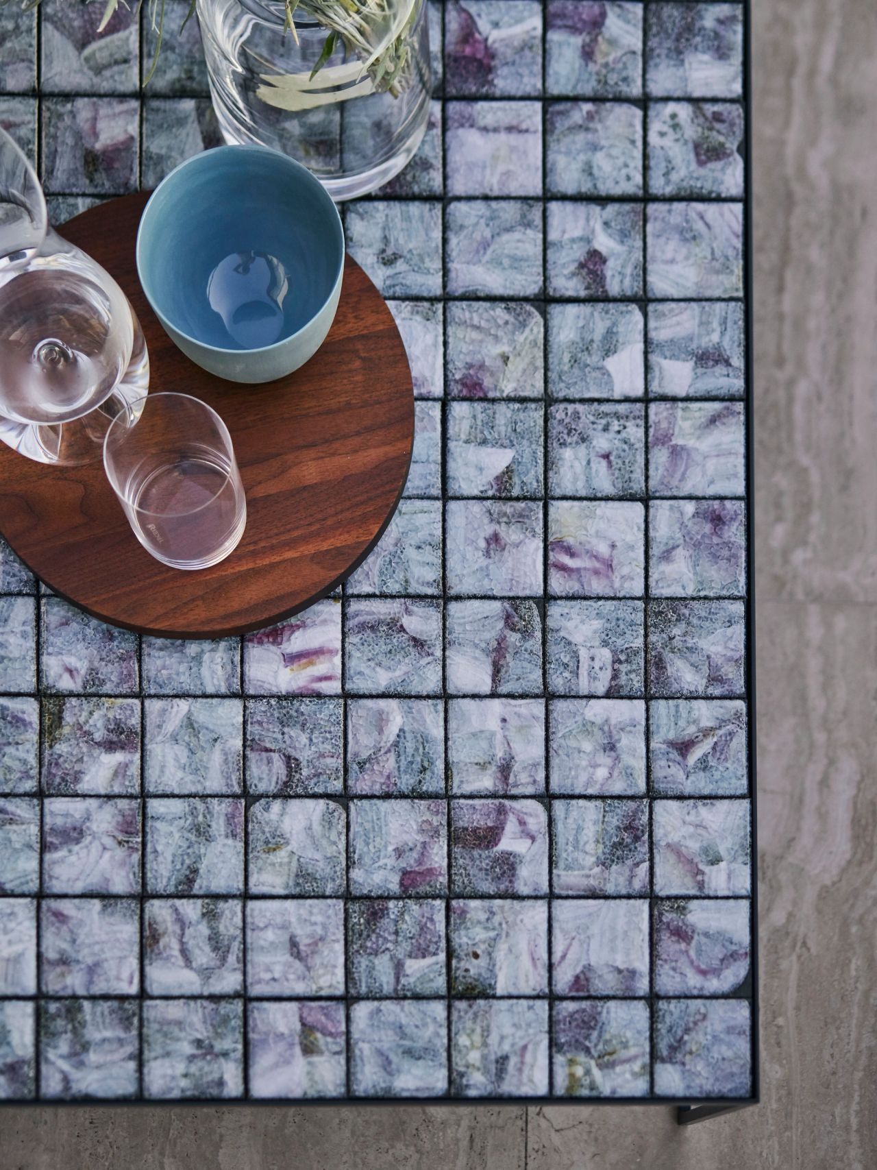 Close-up of a blue and purple mosaic stone coffee table styled with glassware.