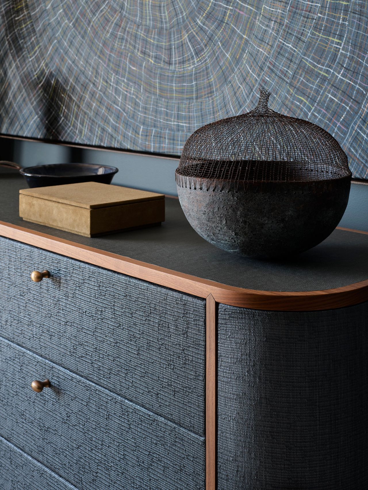 Textured cabinetry, warm timber detailing and a sculptural woven vessel create a richly layered bedroom.
