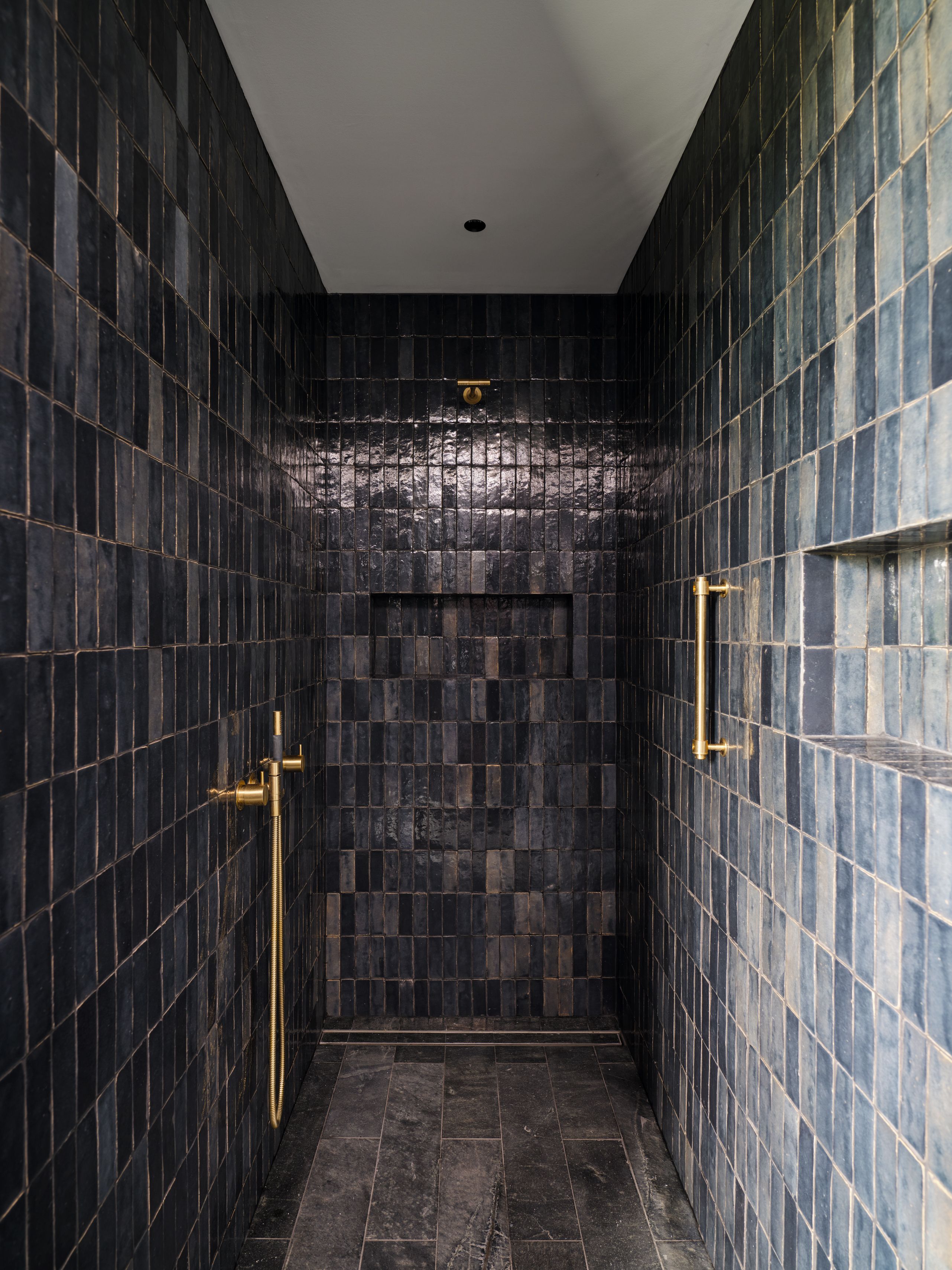 Moody walk-in shower with hand glazed tiles, integrated wall niches and warm brass fixtures in this Margaret River home.