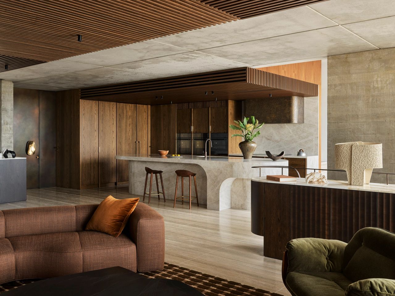 Orla Contemporary open plan living room and kitchen blending Brazilian influences with a warm brown, black, and camel palette; Large white beige quartzite granite kitchen island with timber stools and bronze rangehood