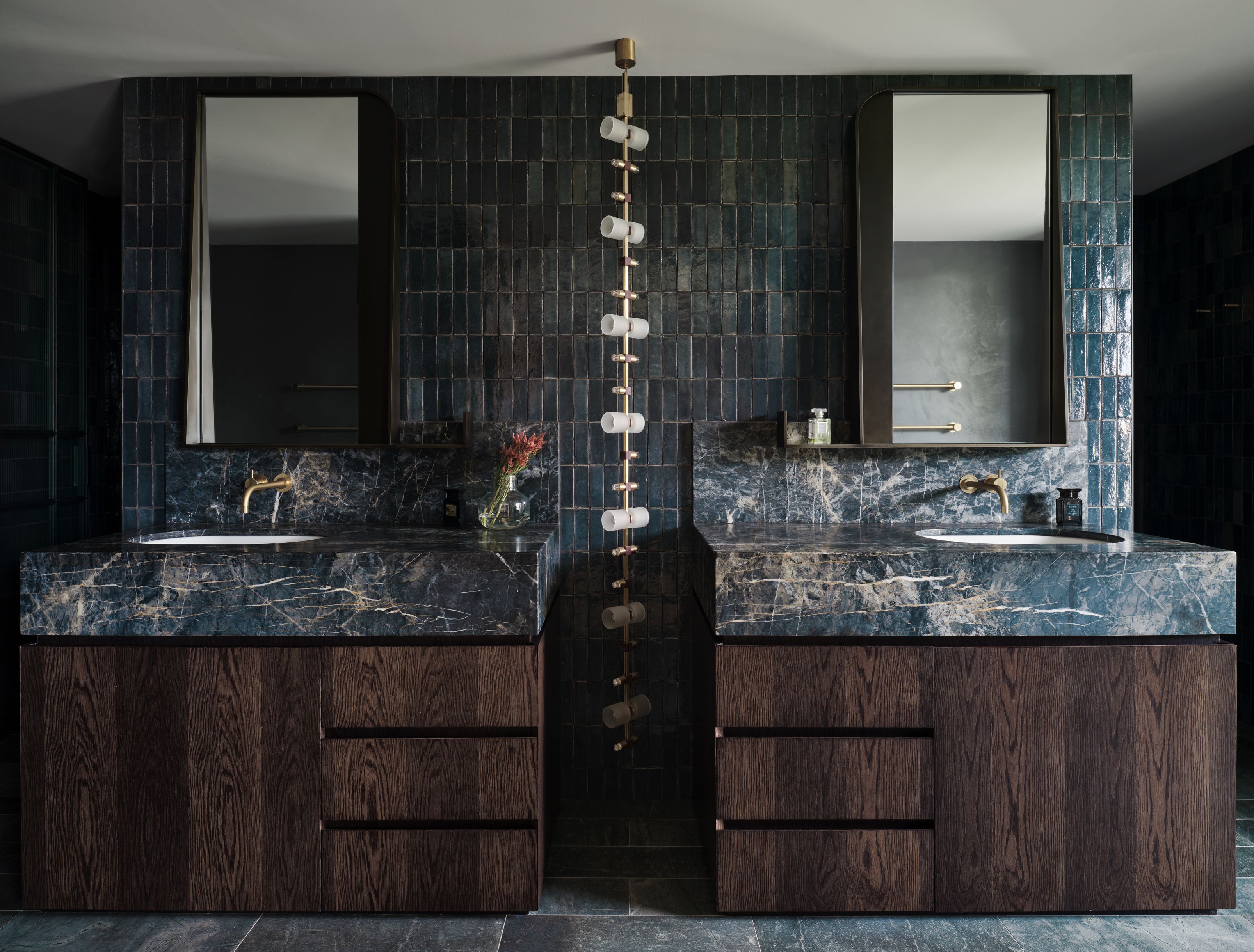 Moody double vanity pairing richly veined dark marble, warm timber cabinetry and handcrafted tiles with refined brass accents.