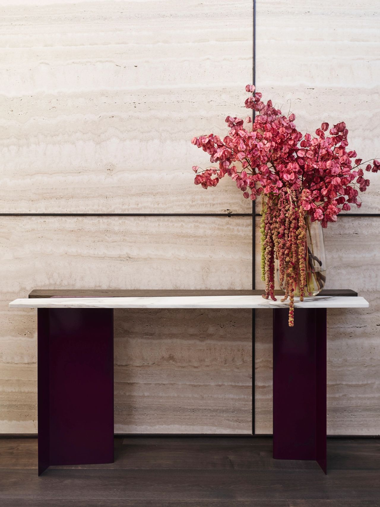 Hill House Entry travertine wall with dark wine coloured console and big vase of pink florals