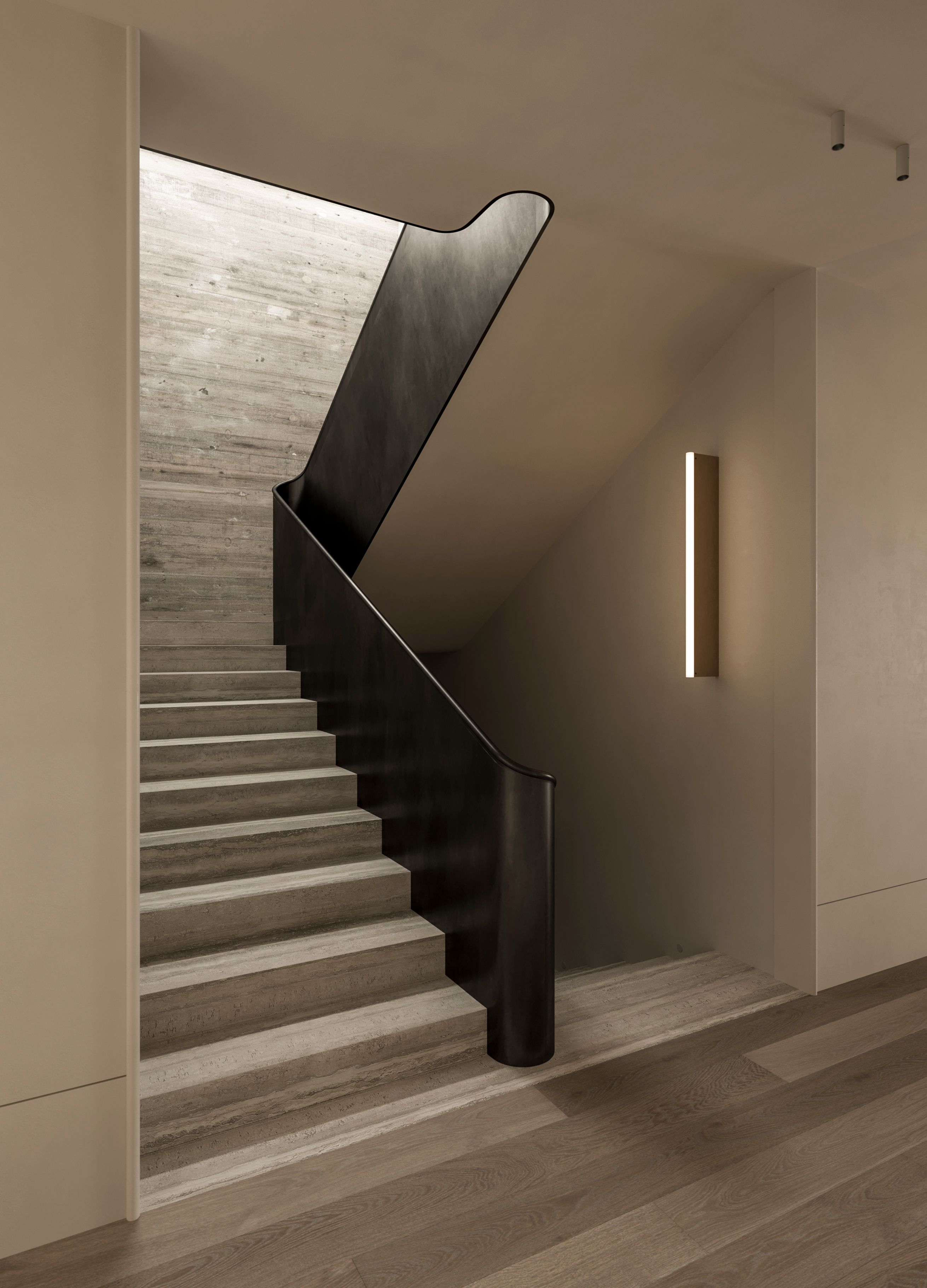 Heavy Metal travertine staircase with a sculptural blackened steel balustrade curving down the stairwell, alongside a slim vertical wall light in a concrete-toned stairwell