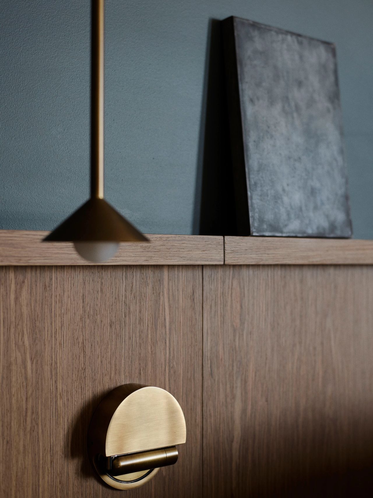 Warm timber joinery and sculptural brass lighting create a refined bedside detail.