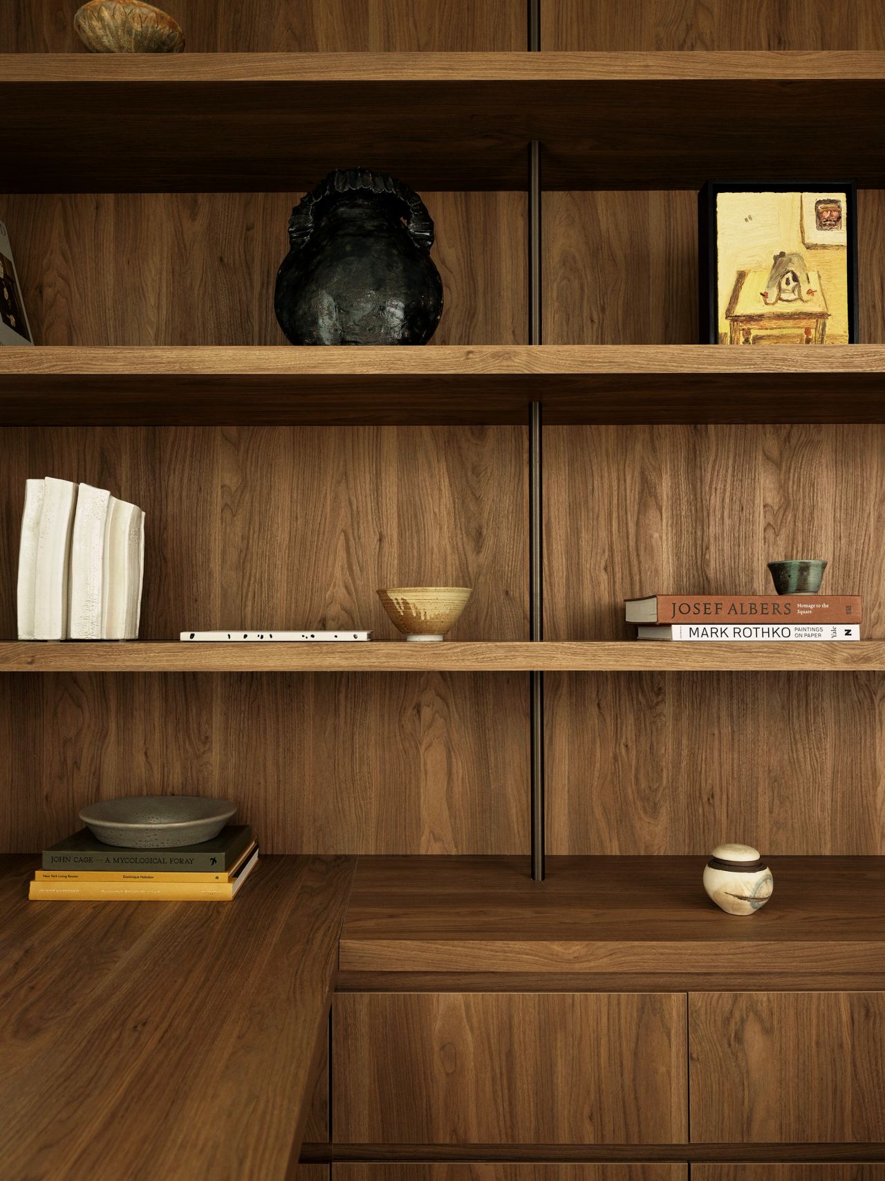 Dancing On The Ceiling Study Joinery Detail Walnut wood bookshelf styled with art monograph books, small ceramic bowls, and a dark sculptural vase.
