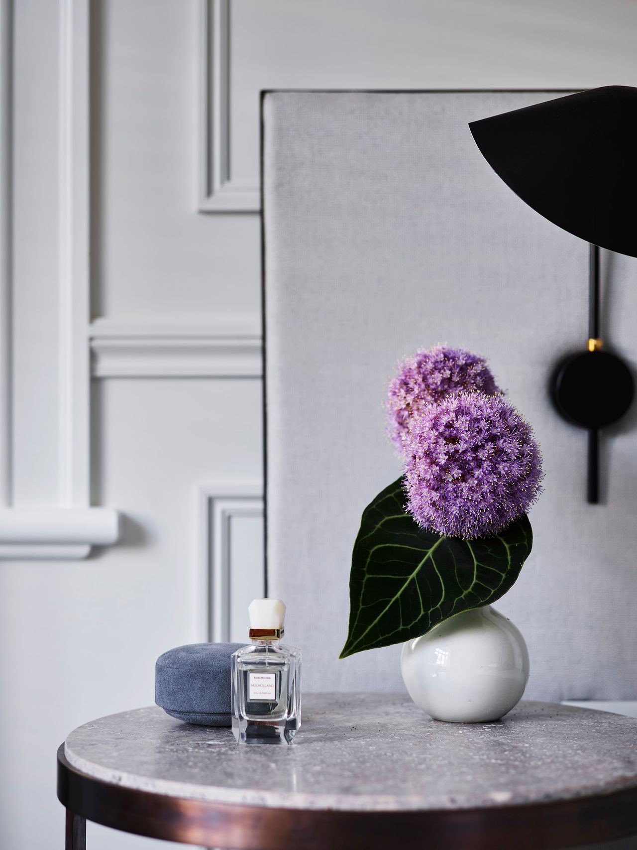 Sculptural purple alliums bring a vivid note of colour to a refined bedside composition of pale stone, and crisp heritage wall detailing.