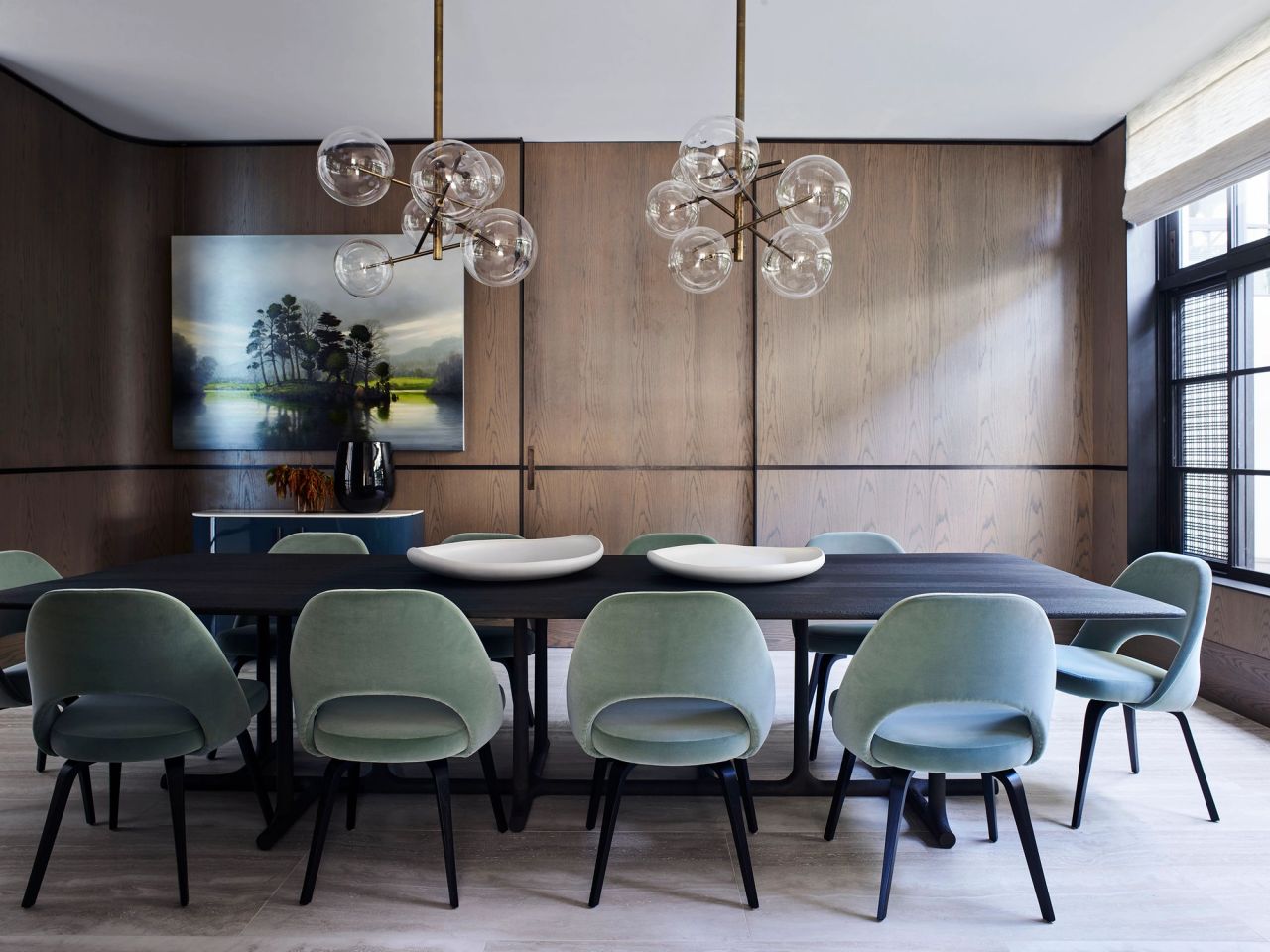 Hill house formal dining room. Light green velvet dining chairs with a dark timber dining table. Glass bubble pendant above