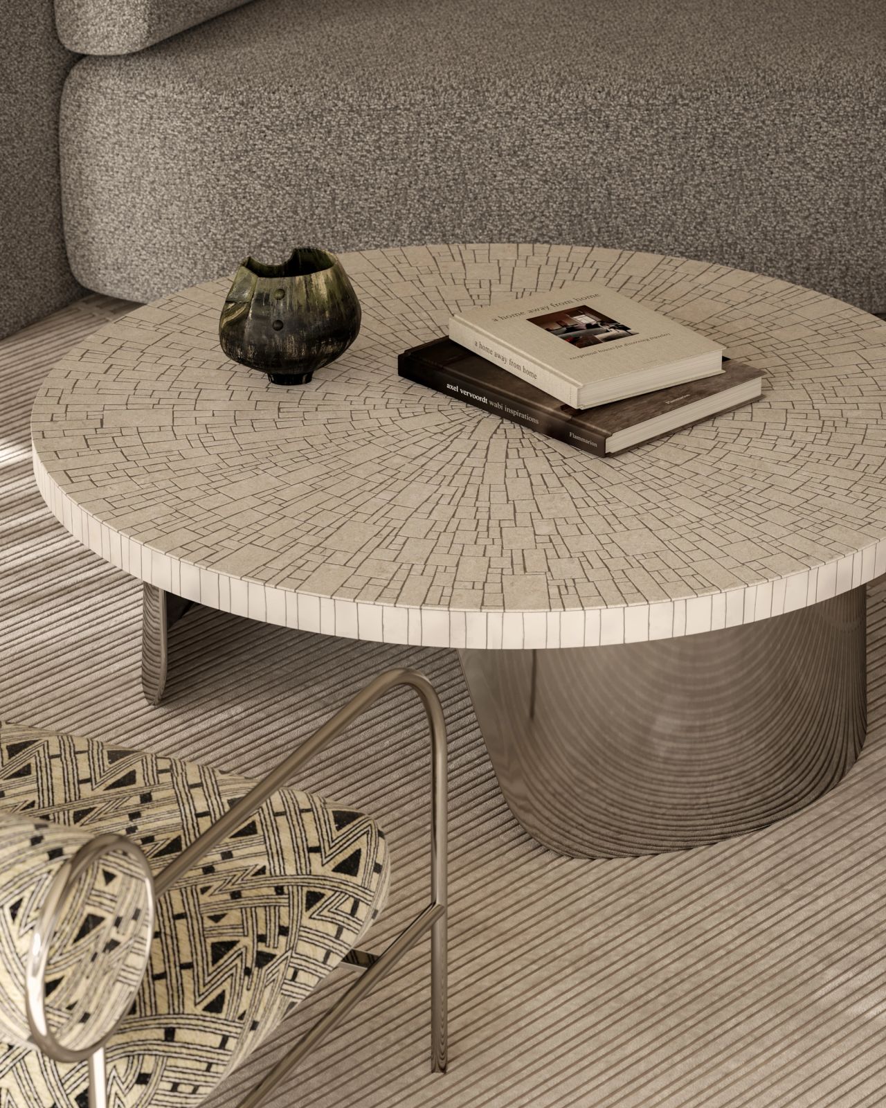 Close-up of a contemporary living room featuring a round, mosaic coffee table, sculptural patterned armchair, textured neutral sofa and layered natural materials.