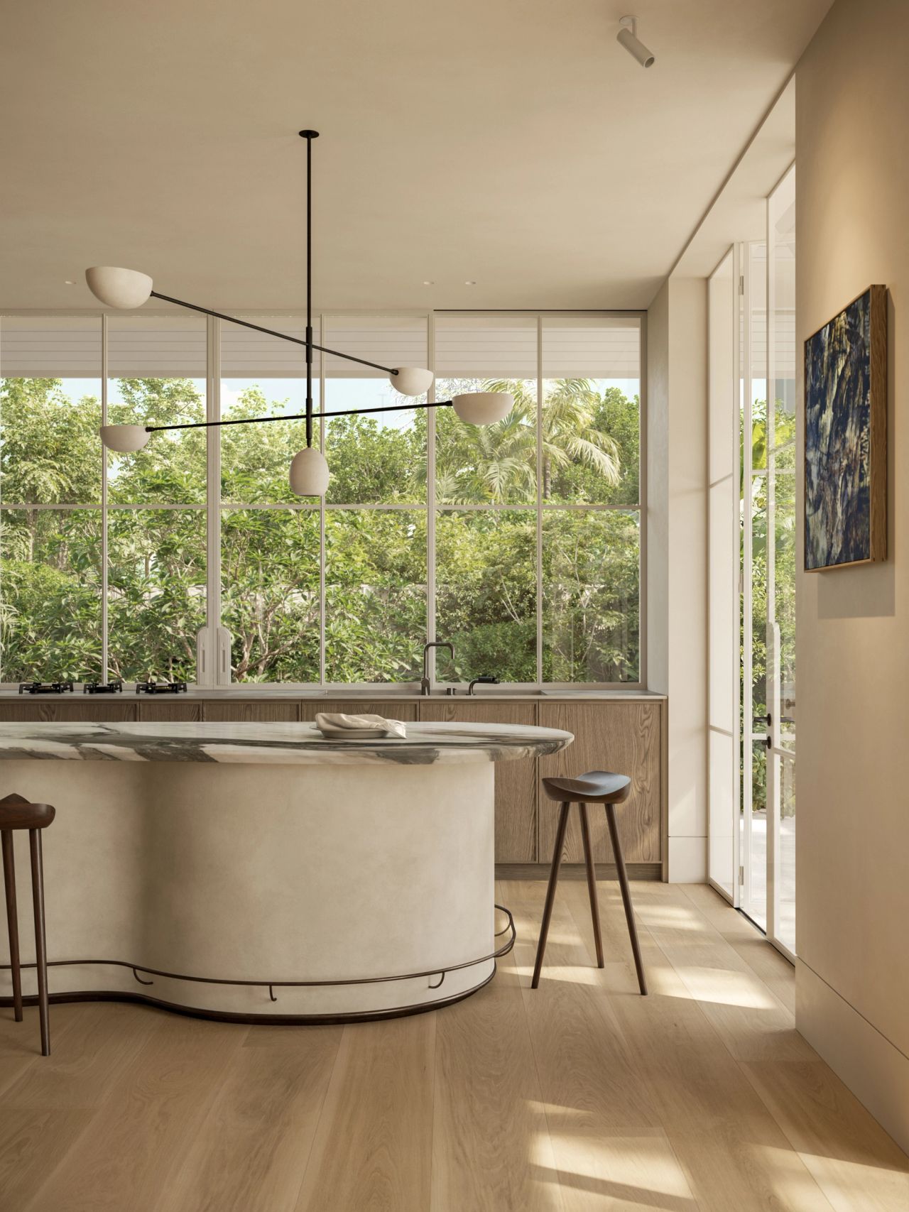 Kitchen with a curved marble-topped island and plaster-finish base, timber cabinetry, and a sculptural multi-arm pendant light with matte white shades. Floor-to-ceiling windows frame lush garden greenery, with timber bar stools and framed artwork completing the space.