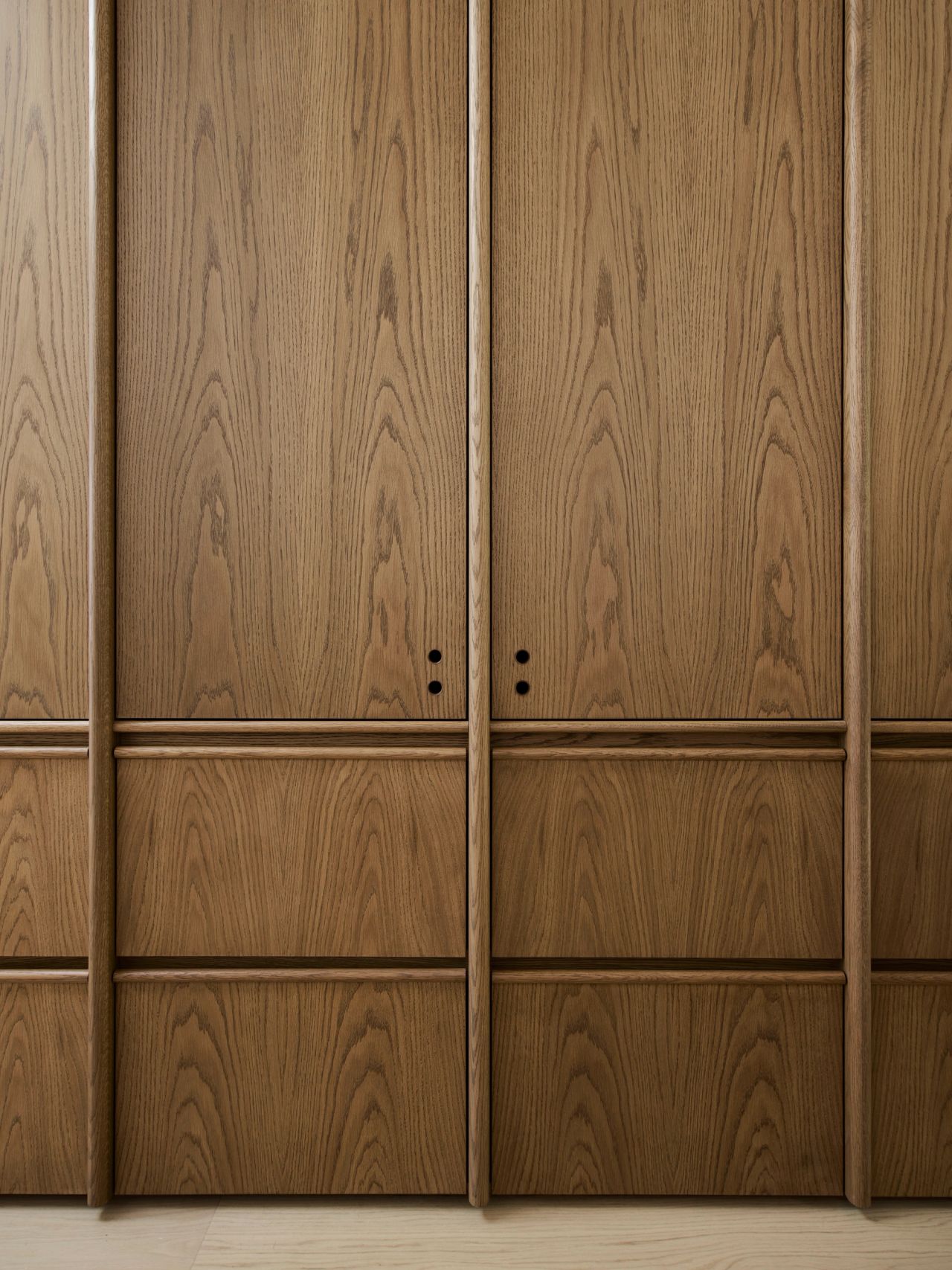 Ultramarine Close-up of oak panelled cabinetry doors with fine round push-latch details and slim vertical trim