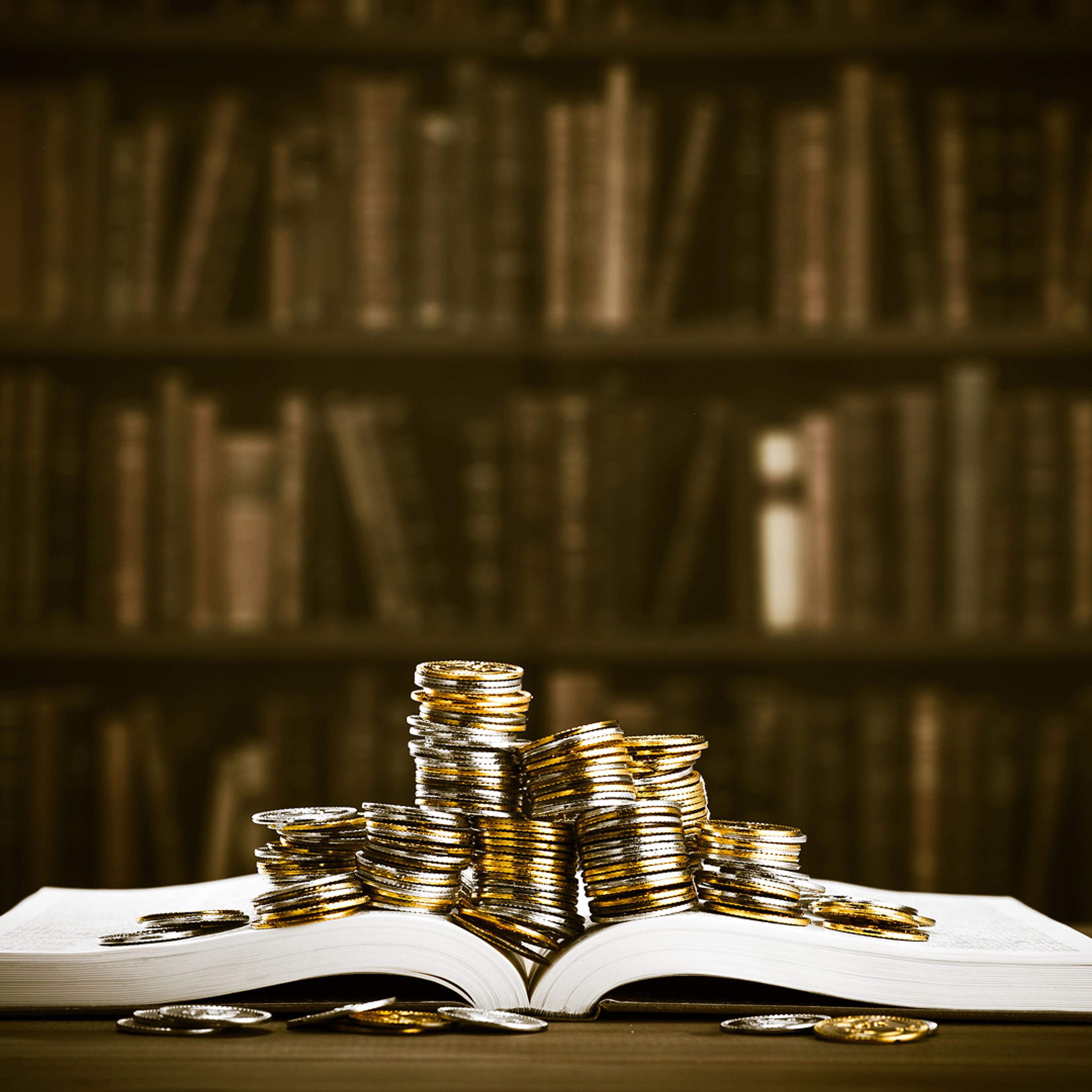 En åpen bok med mynter i stabler oppå