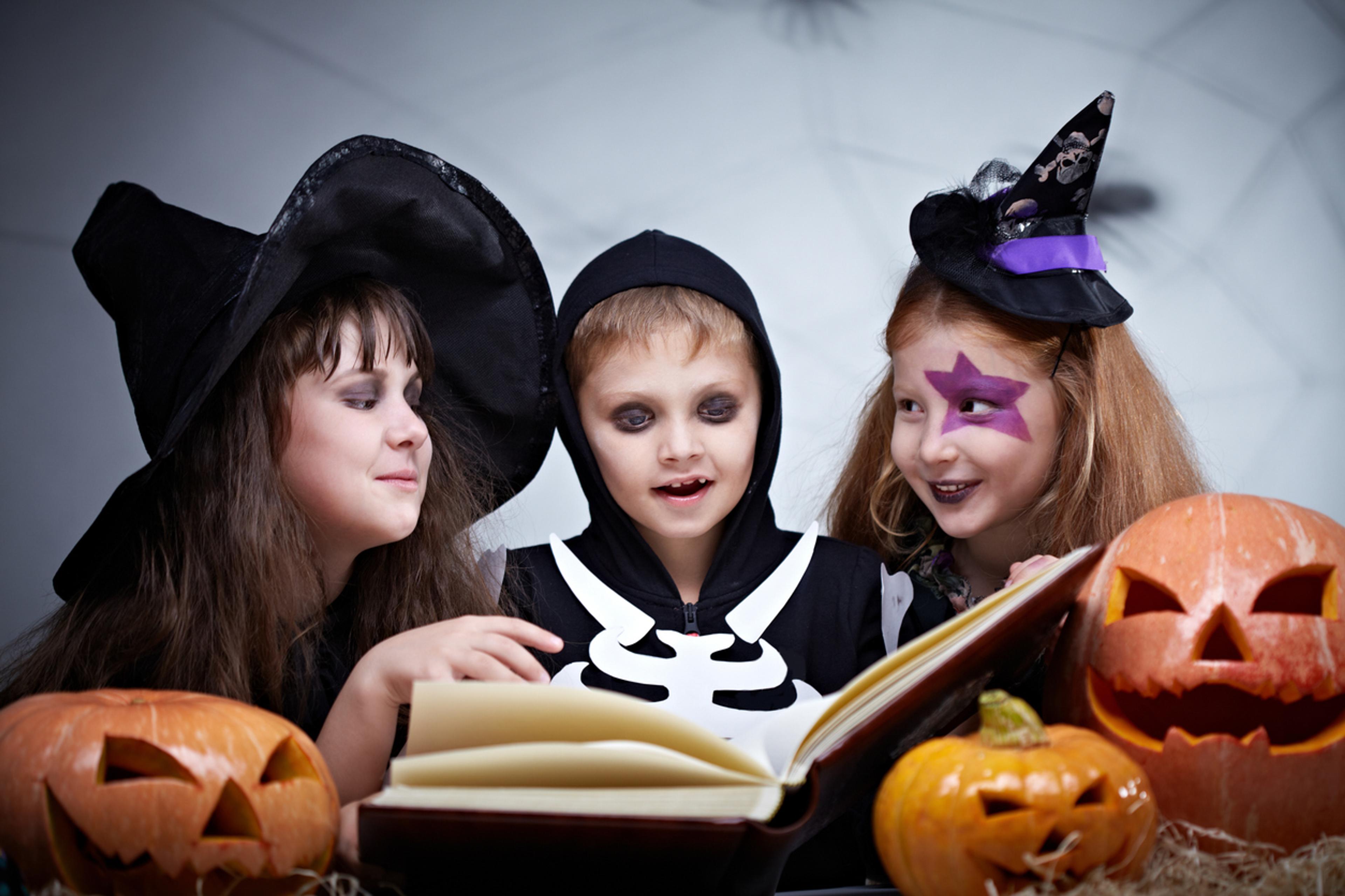 Halloween-utkledde barn som leser en bok