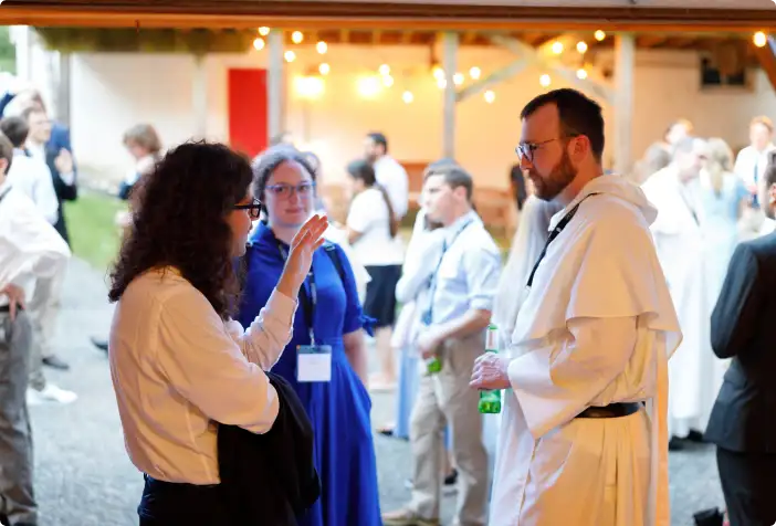 Women talking to a friar at a Thomistic Institute event