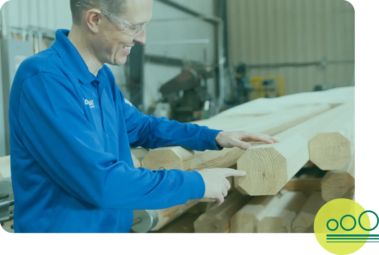 A smiling man pointing at wood