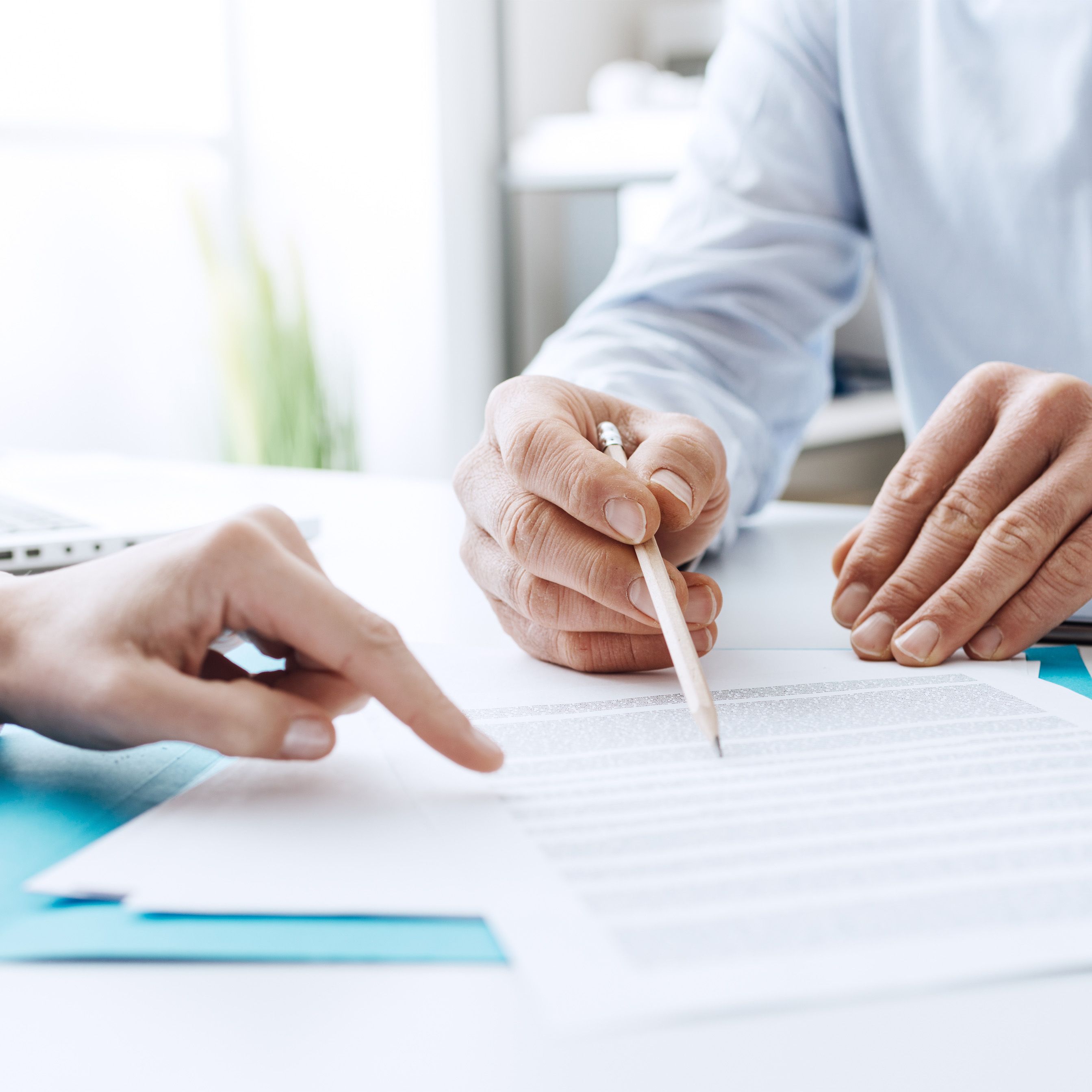 Two people signing legal papers to sell a business.