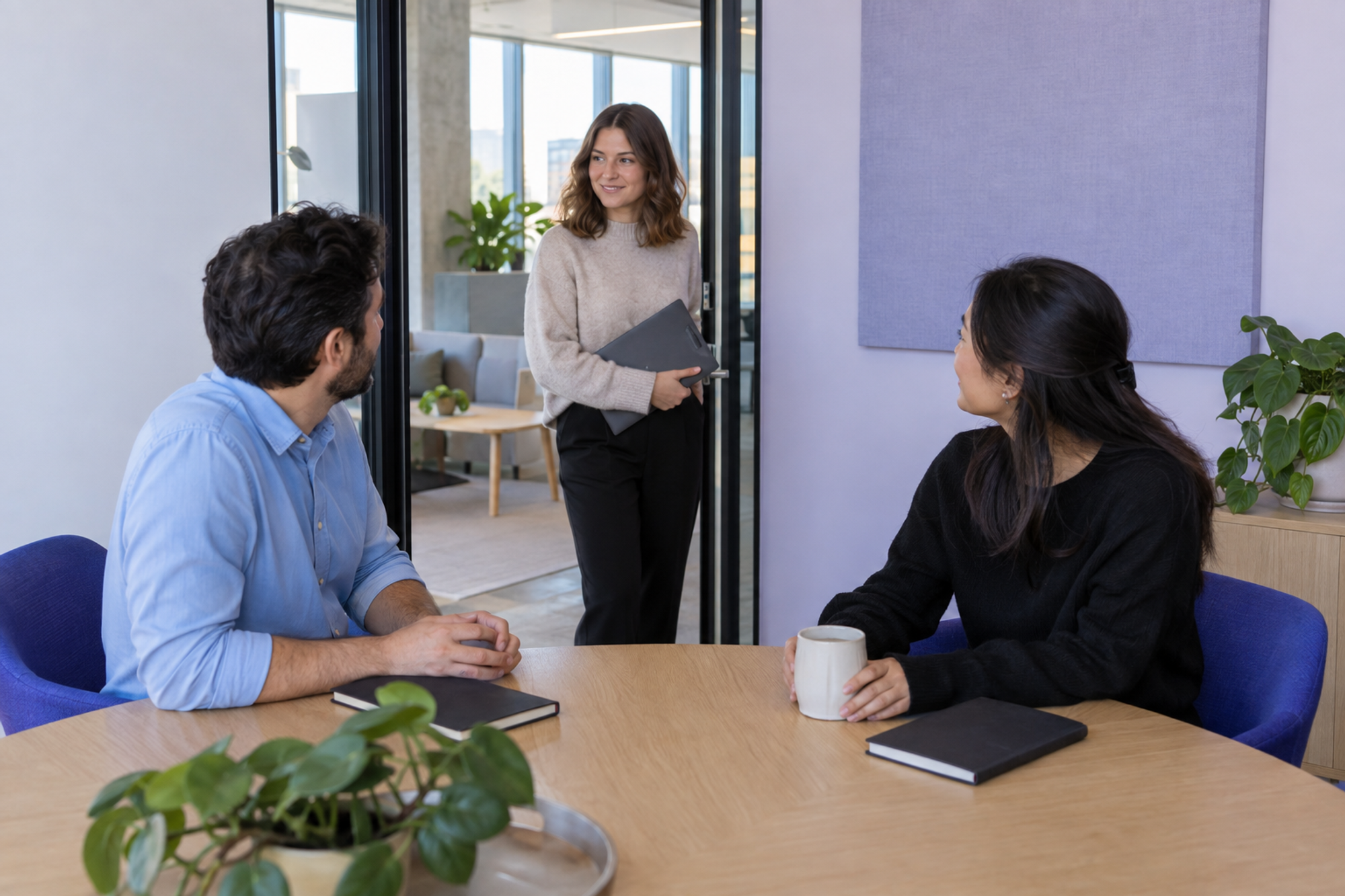 A workplace coordinator checks with two colleagues who are already using a meeting room.