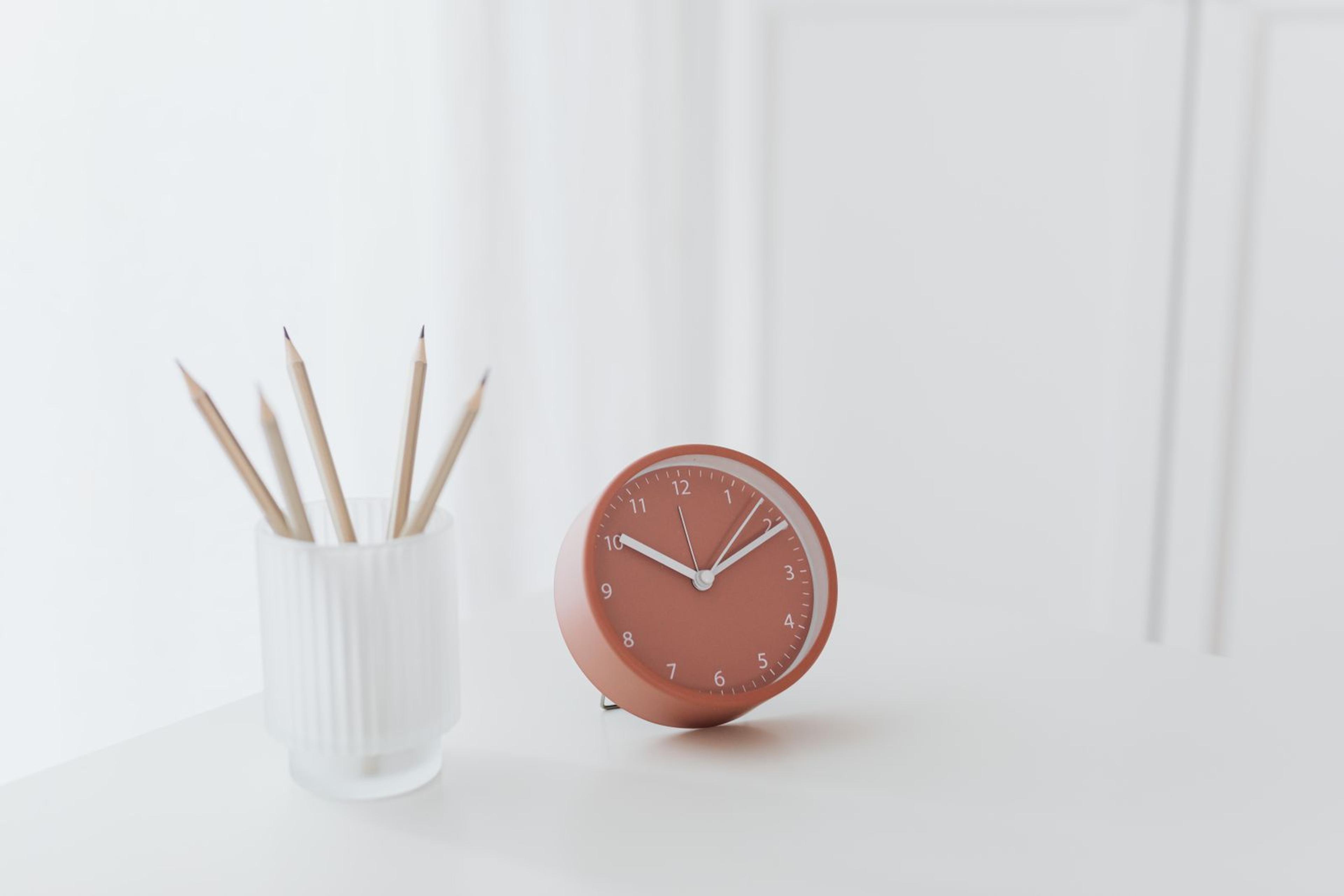 Horloge posée sur un bureau à côté de crayons