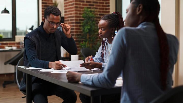 Research team meeting about a project's financial status in an office