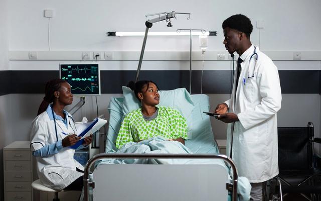 African doctors consulting a young adult patient in a hospital ward