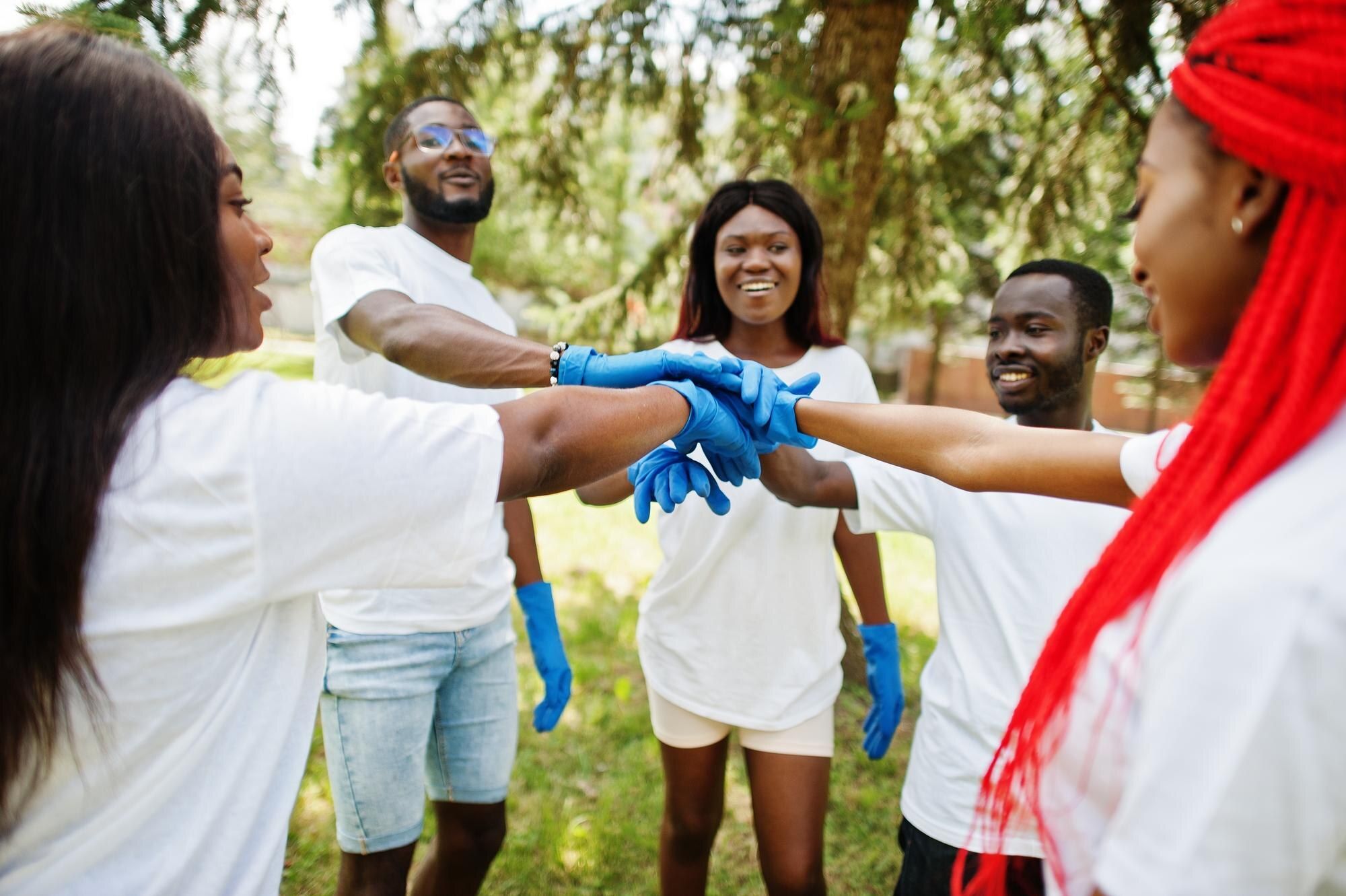 Group of African volunteers joining hands together in a park