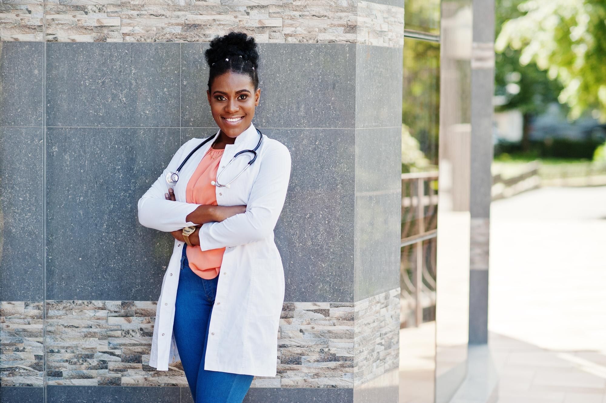 African American doctor in lab coat with stethoscope, outdoor portrait