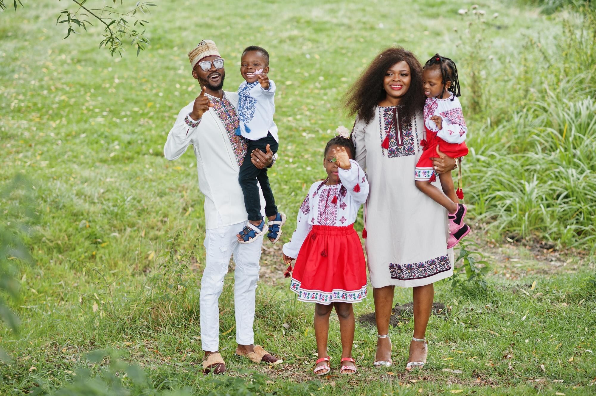 African family in traditional clothes posing together at a park