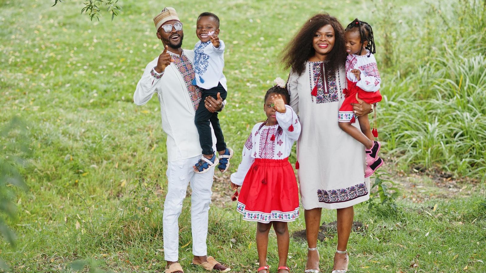 African family in traditional clothes posing together at a park