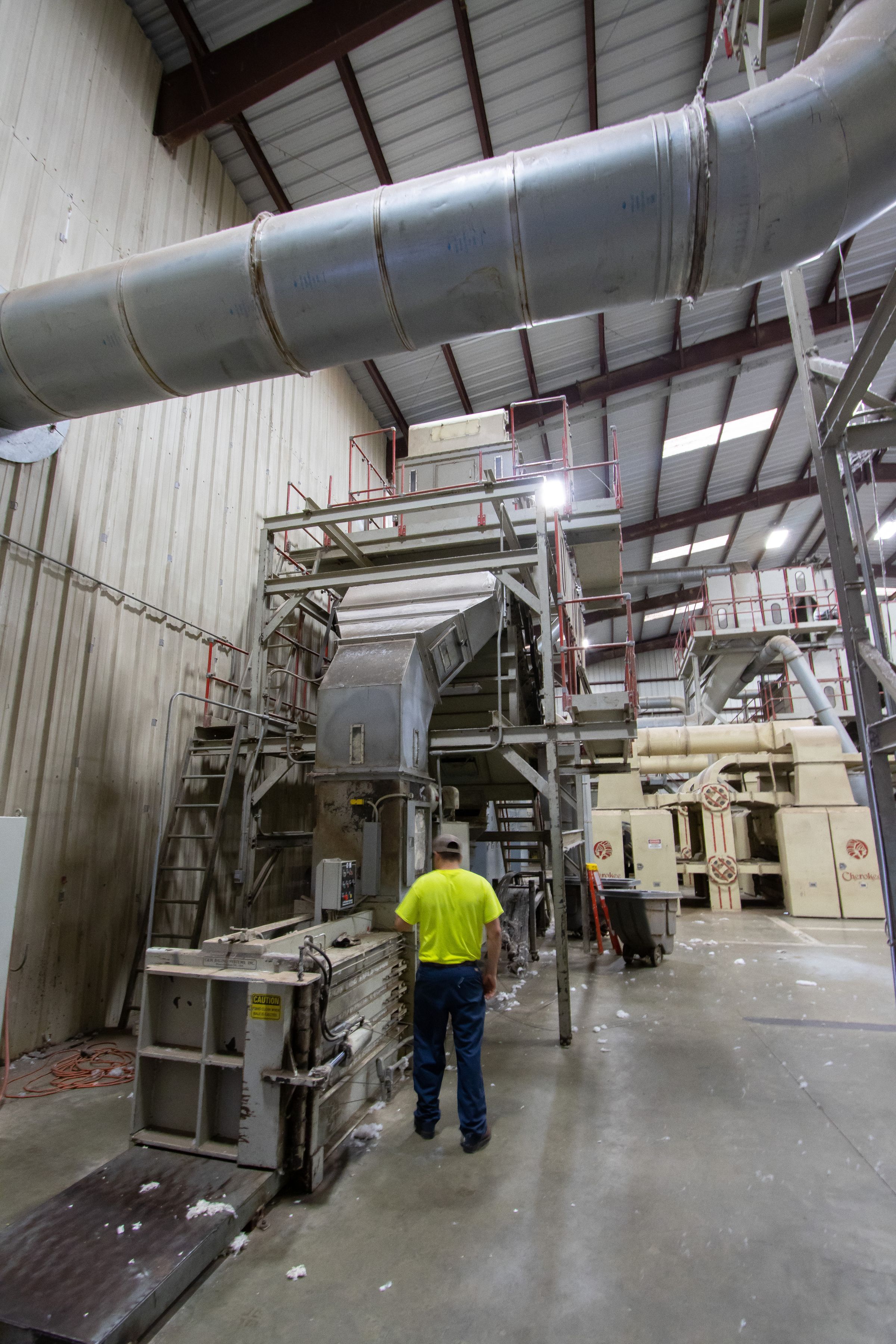 Industrihall med sorteringsutrustning och en operatör i varselkläder.
