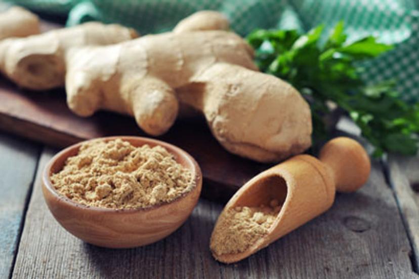 Fresh ginger root and ground ginger spice on wooden background