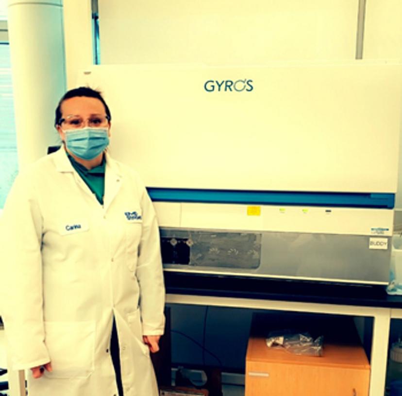 Carina Carter stands in front of the Gyrolab automated immunoassay platform