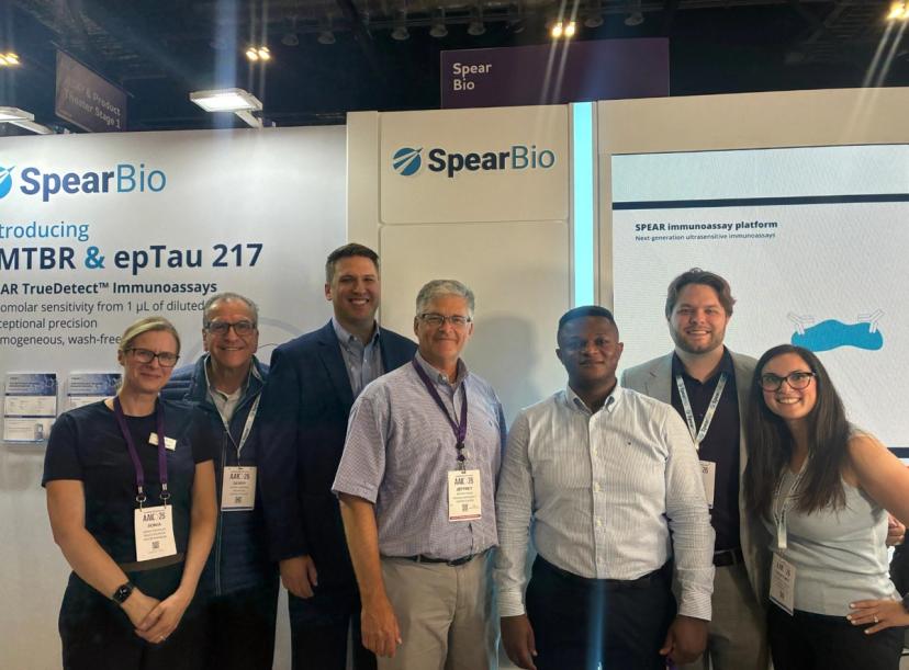 Sonia Nicholas with Gerry Andros, Oliver Tassinari, Dr. Jeffrey Dage, Dr. Thomas Karikari, Sam Olson, and Courtney Shirley at the Spear Bio booth during AAIC 2026