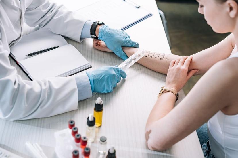 allergist holding ruler near marked hand of woman