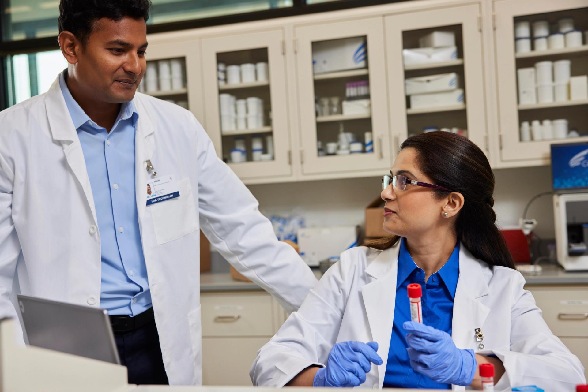 Two clinical laboratory professionals discussing workflows in a hospital lab setting