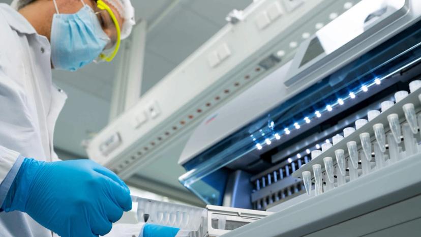 Image of a scientist placing a rack of test tubes into the QIAGEN EZ2 Connect benchtop instrument