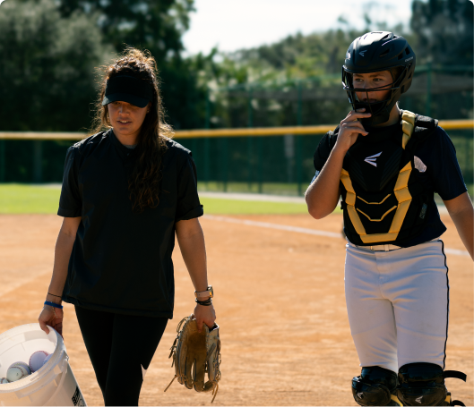 Female coach walking with athlete, carrying and wearing gear