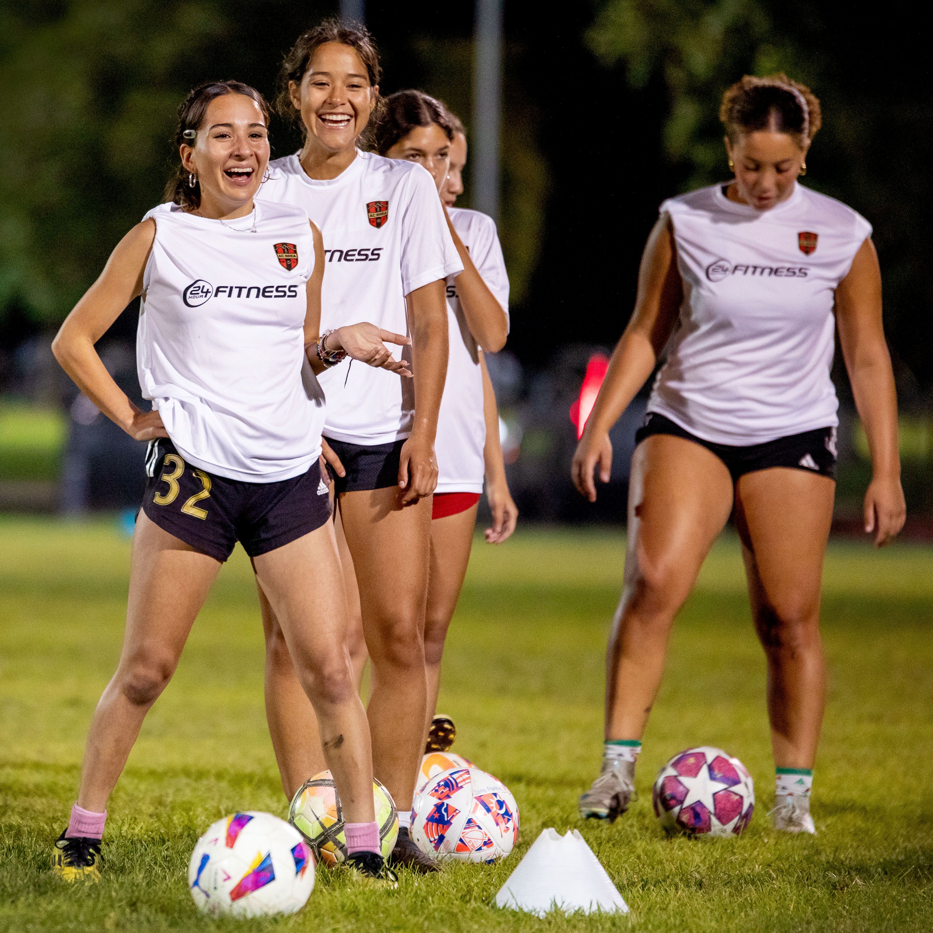 Young female athletes lined up at a night practice in 24 Hour Fitness warm-up shirts